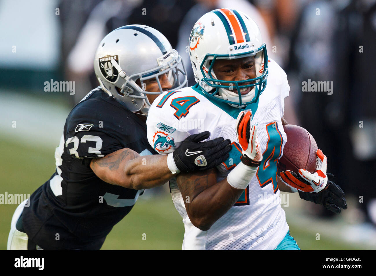 November 28, 2010; Oakland, CA, USA;  Miami Dolphins wide receiver Marlon Moore (14) breaks a tackle from Oakland Raiders safety Tyvon Branch (33) during the third quarter at Oakland-Alameda County Coliseum. Miami defeated Oakland 33-17. Stock Photo