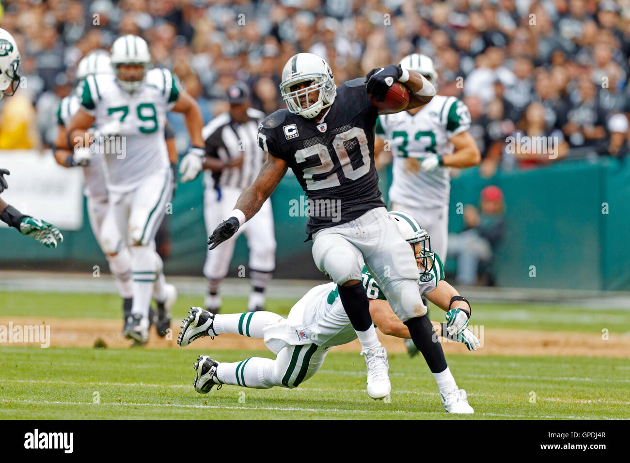 Sep 25, 2011; Oakland, CA, USA;  Oakland Raiders running back Darren McFadden (20) breaks a tackle from New York Jets strong safety Jim Leonhard (36) on a 70 yard touchdown run during the second quarter at O.co Coliseum. Stock Photo