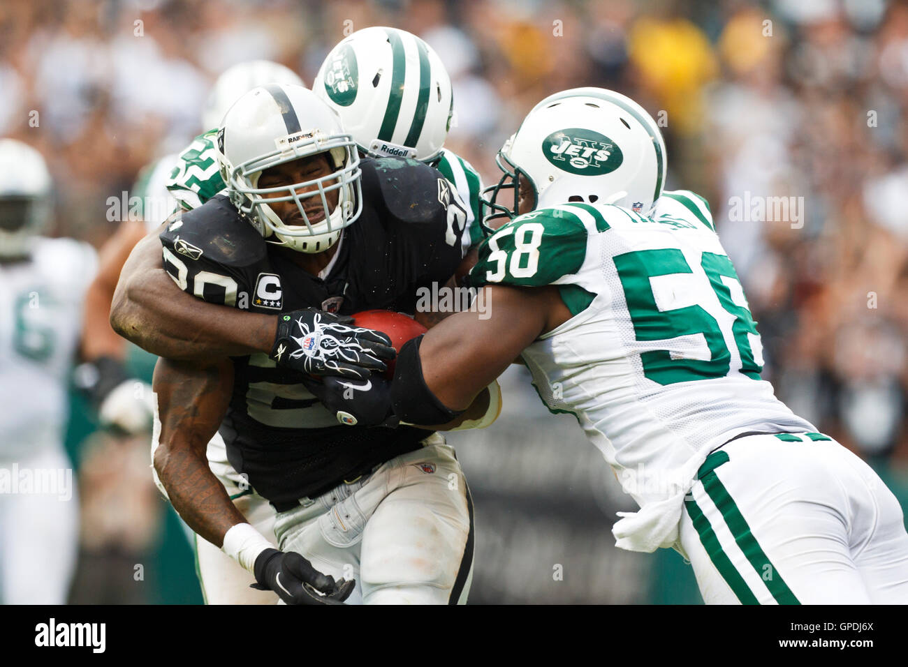 Sep 25, 2011; Oakland, CA, USA;  Oakland Raiders running back Darren McFadden (20) is tackled by New York Jets outside linebacker Bryan Thomas (58) and inside linebacker David Harris (back) during the third quarter at O.co Coliseum. Oakland defeated New Y Stock Photo