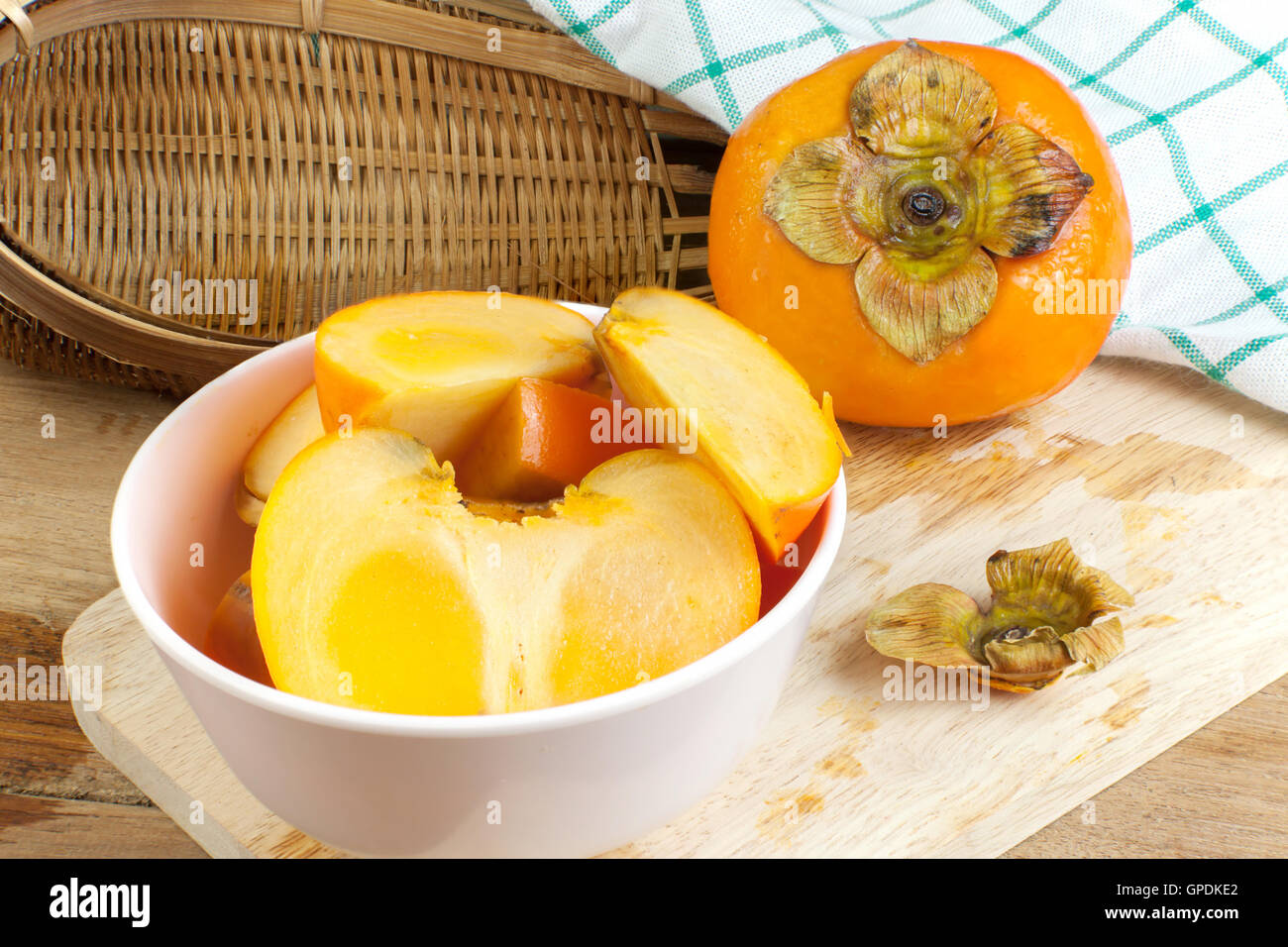 Persimmon yellow color ripe split fruits on wood table Stock Photo