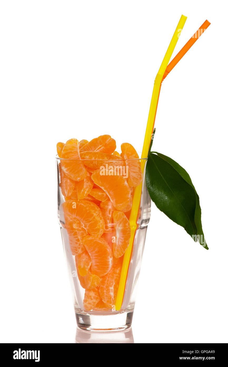 Big glass filled with orange mandarin citrus fruit slices, decorated with straw and green leafs representing fresh natural juice Stock Photo