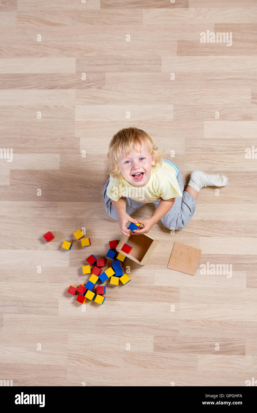 top view of happy kid playing with colorful toys on floor Stock Photo