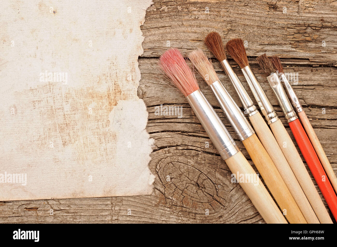 Paint brushes on old wooden background with blank vintage paper Stock Photo