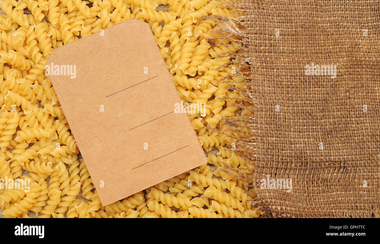 raw pasta and price tag on wood as background Stock Photo