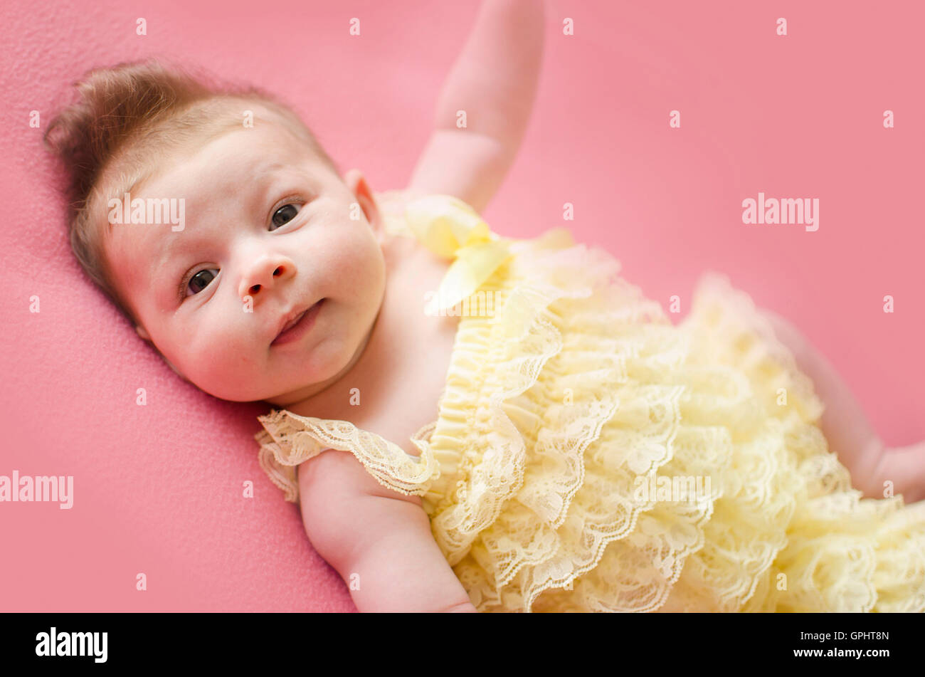 adorable two months old baby girl lying on her back on a pink blanket Stock Photo