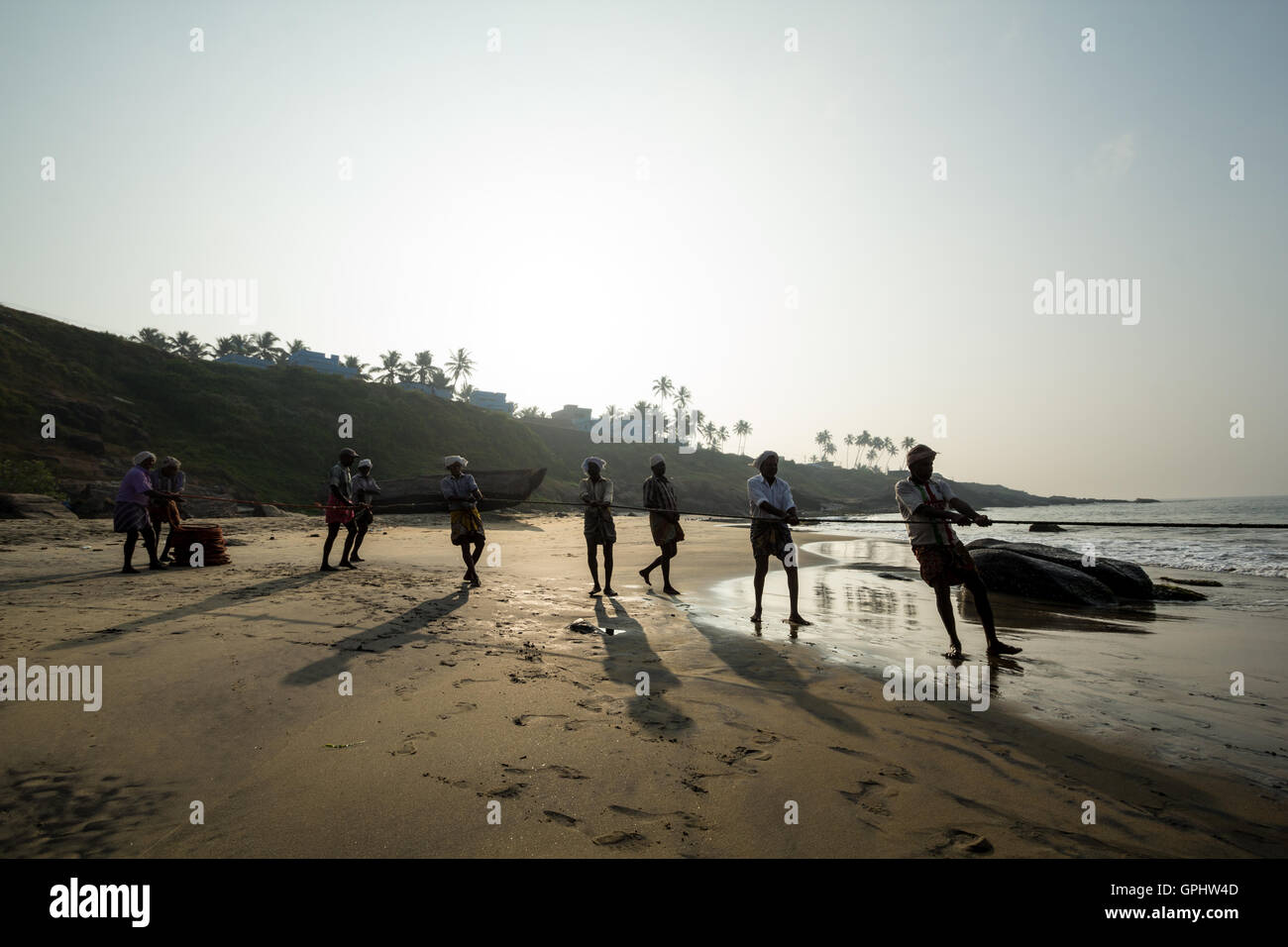 Fishermen hauling in nets at sunrise, Vizhinjam Beach, Kovalam, Kerala,India, Asia Stock Photo