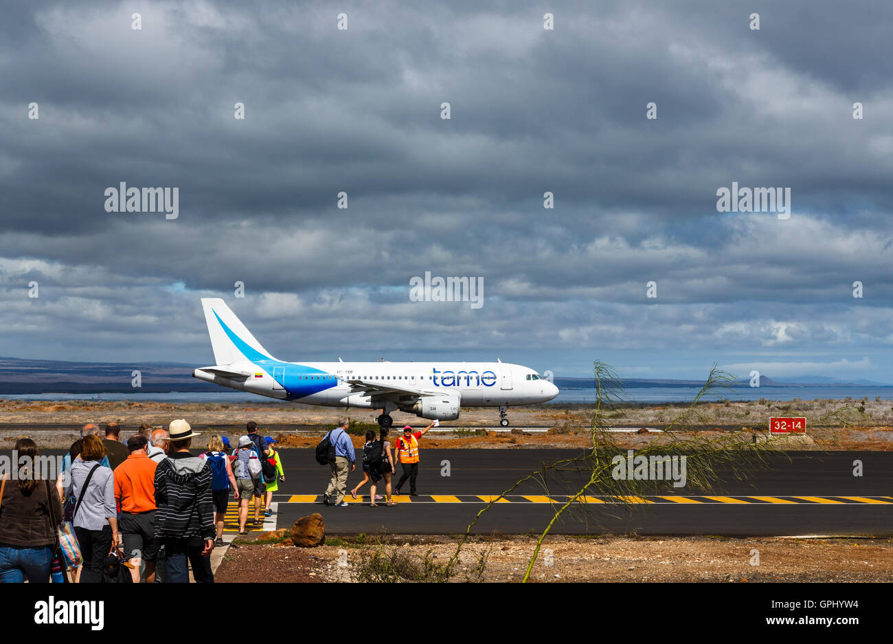 Passengers boarding a TAME airline A320 Airbus on the runway at Baltra, Galapagos Islands, Ecuador, under gathering rain clouds Stock Photo