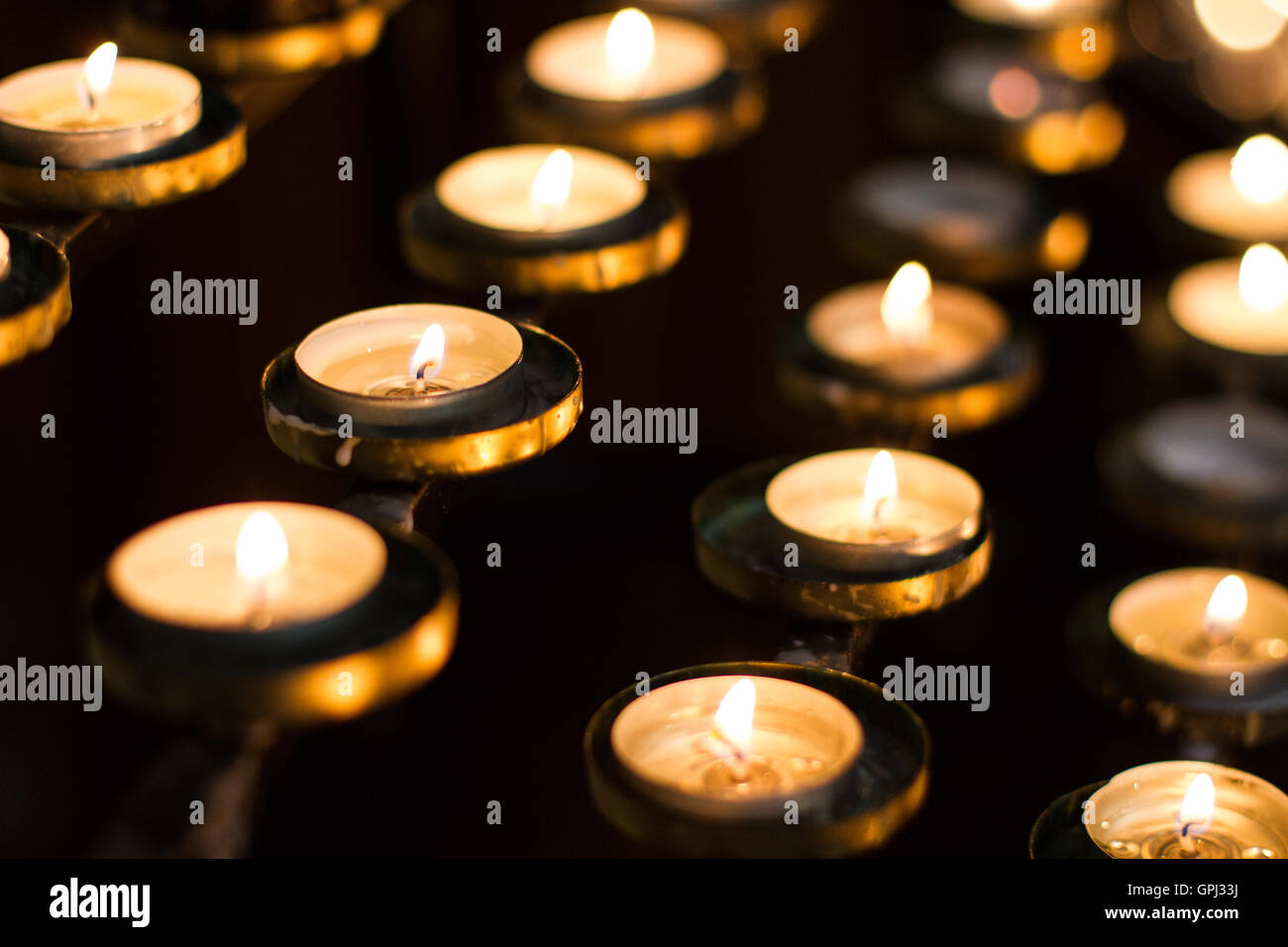 Rows of lit church candles remembering the dead and loved ones Stock