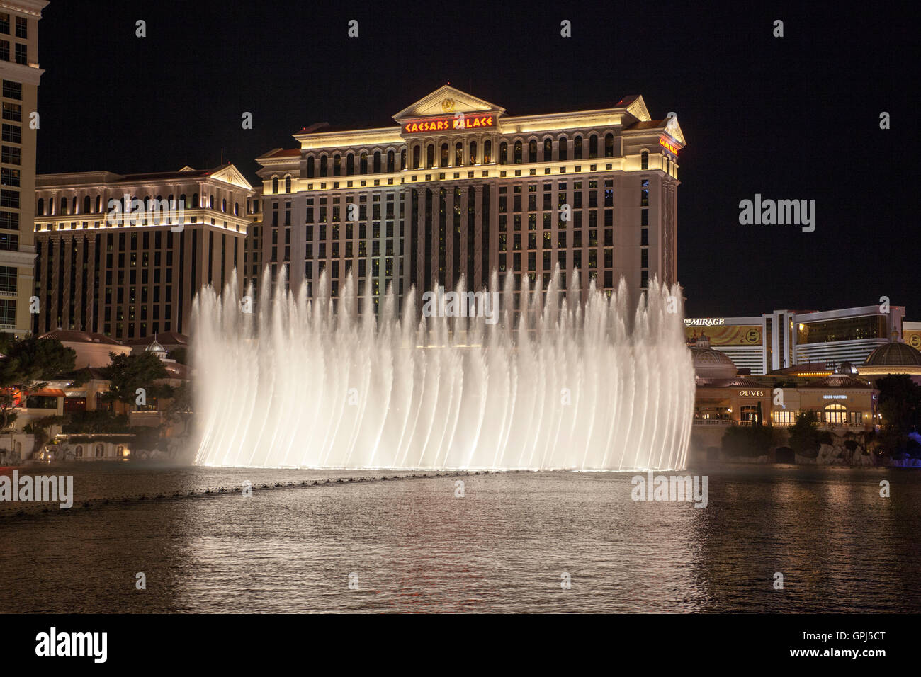 Caesars Palace in Las Vegas Nevada with the fountains of the The Bellagio hotel in the foreground at night Stock Photo