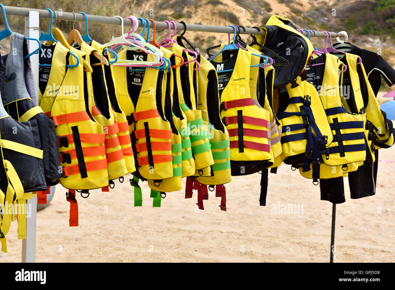 Rack of life jackets on beach hanging ready for watersports Stock Photo -  Alamy