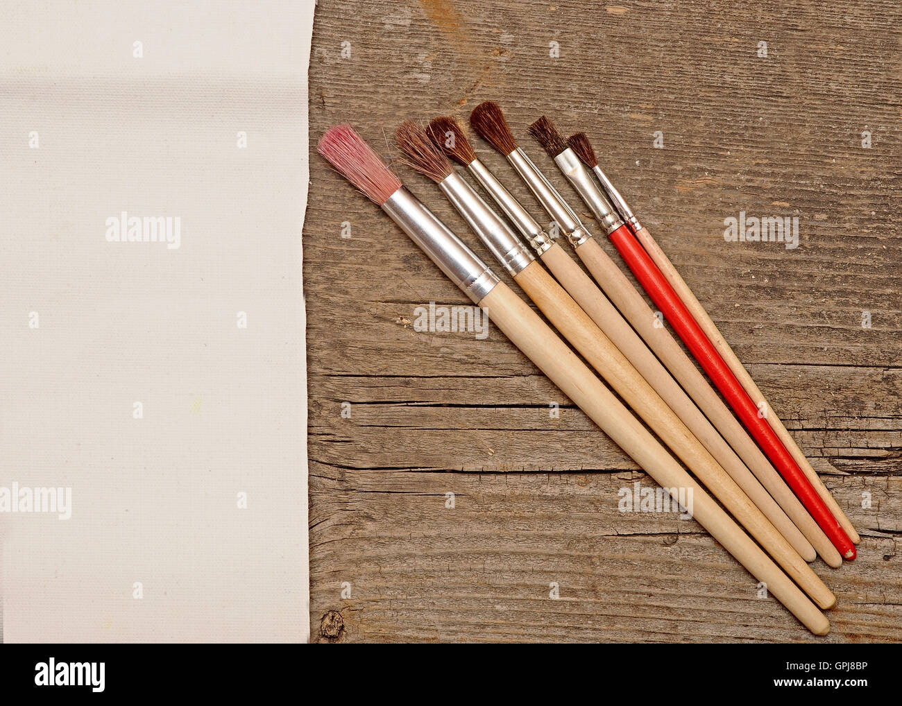 Paint brushes on old wooden background with white canvas Stock Photo