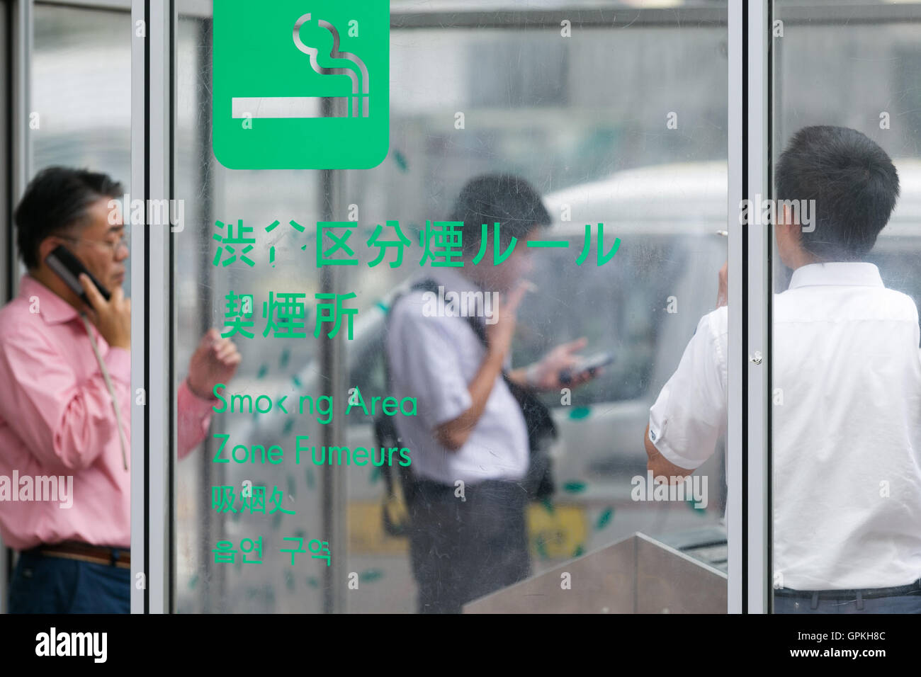 People smoke in a designated smoking area outside Shibuya station on
