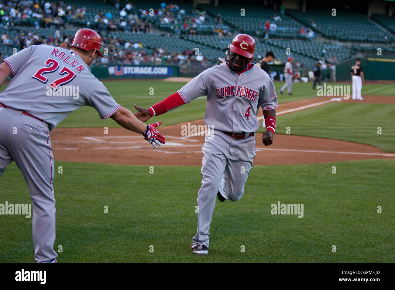 June 21, 2010; Oakland, CA, USA;  Cincinnati Reds second baseman Brandon Phillips (4) celebrates with third baseman Scott Rolen (27) after scoring a run against the Oakland Athletics during the first inning at Oakland-Alameda County Coliseum. Stock Photo