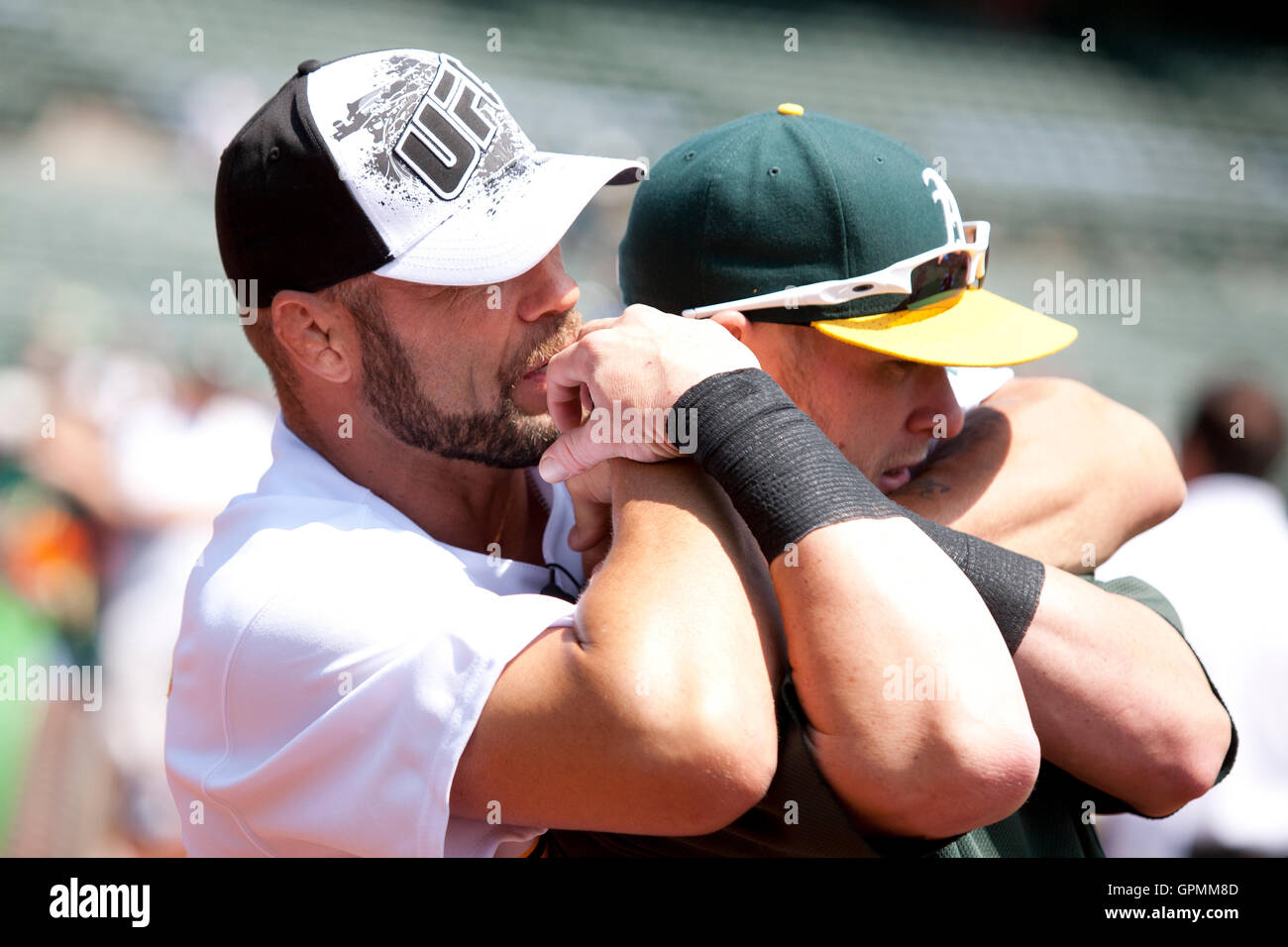 August 7, 2010; Oakland, CA, USA;  Ultimate Fighting Championship fighter Randy Couture demonstrates a choke hold on Oakland Athletics first baseman Daric Barton (10) before the game against the Texas Rangers at Oakland-Alameda County Coliseum. Stock Photo