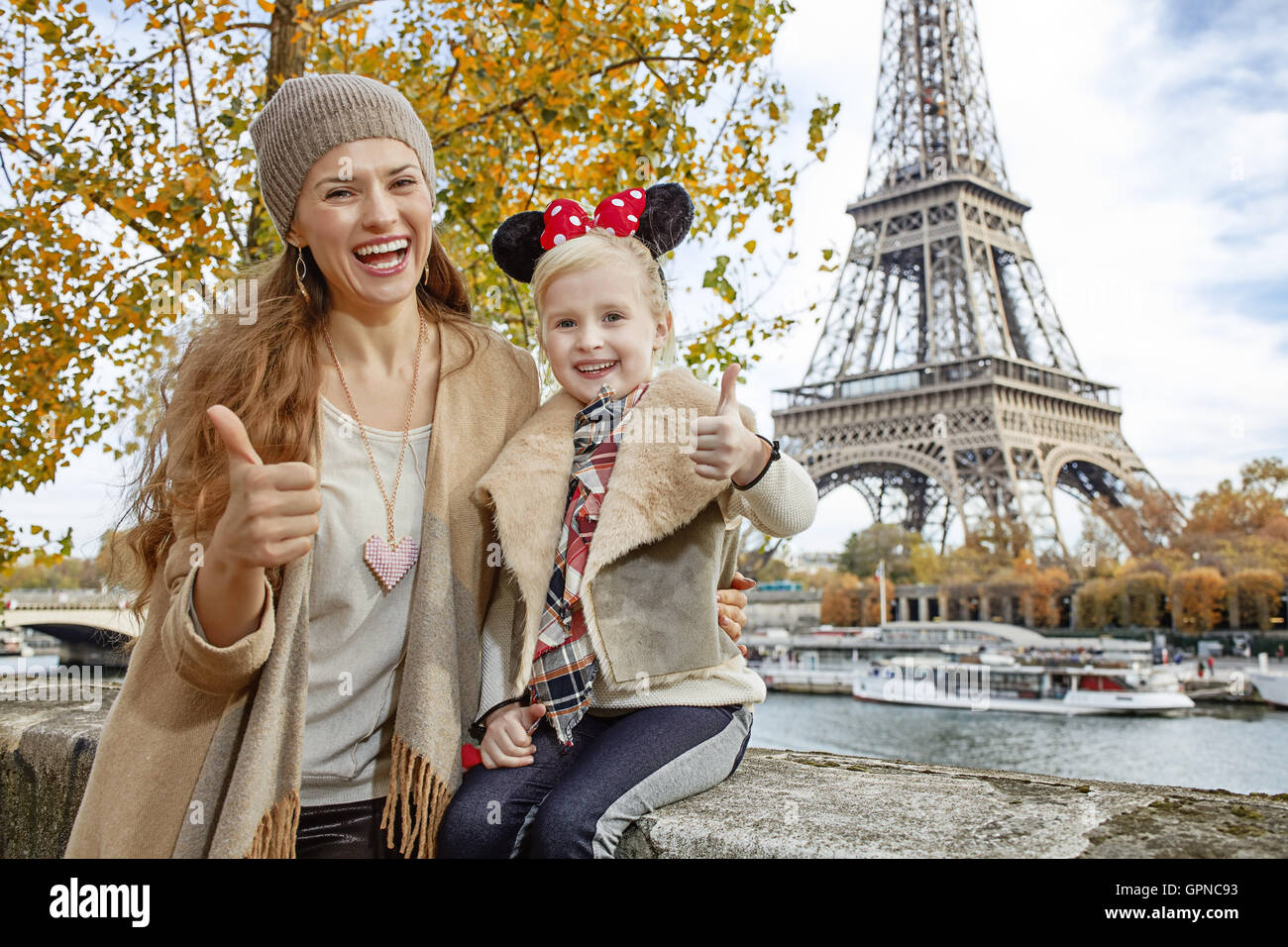 Perfect autumn holidays in Disneyland and Paris. Portrait of smiling tourists mother and daughter in Minnie Mouse Ears on embank Stock Photo