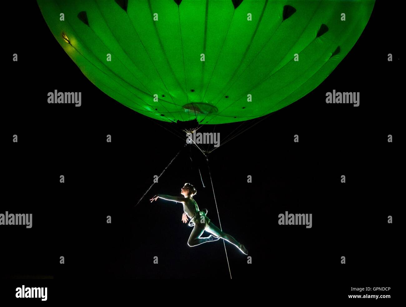 An acrobat is suspended below the Heliosphere, a giant helium balloon, as she performs during the Freedom Festival in Hull. Stock Photo