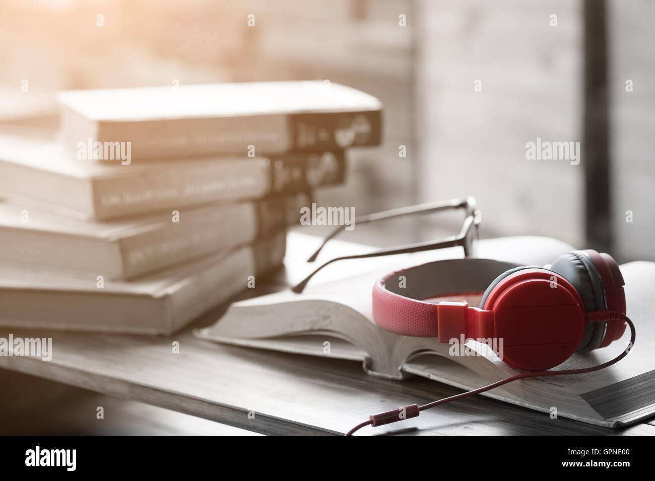 Red headphone on book in cafe or library,morning light and selective colour process Stock Photo