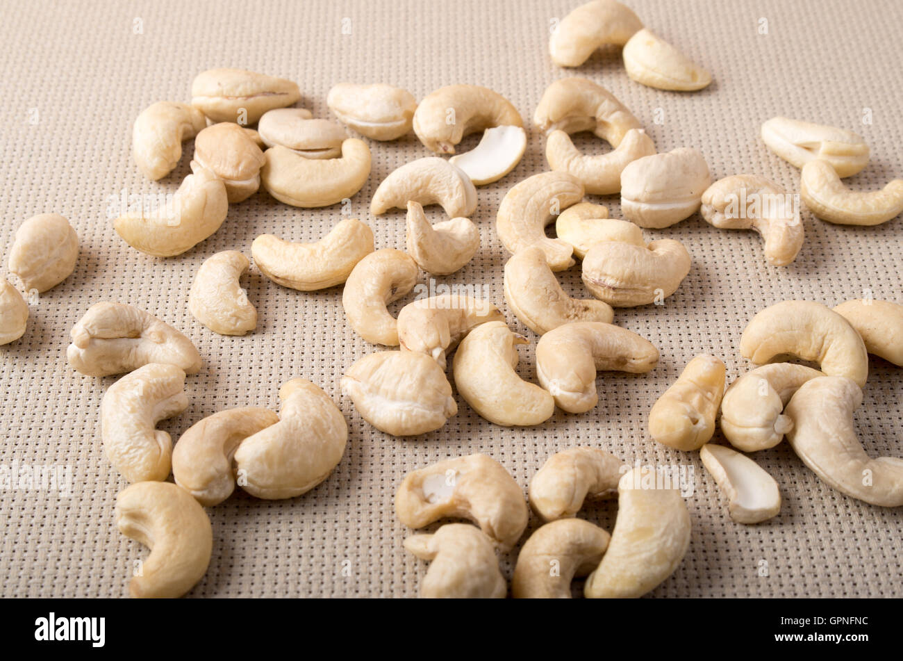 Closeup view on raw cashew nuts scattered on the surface of the table on the background of the fabric Stock Photo
