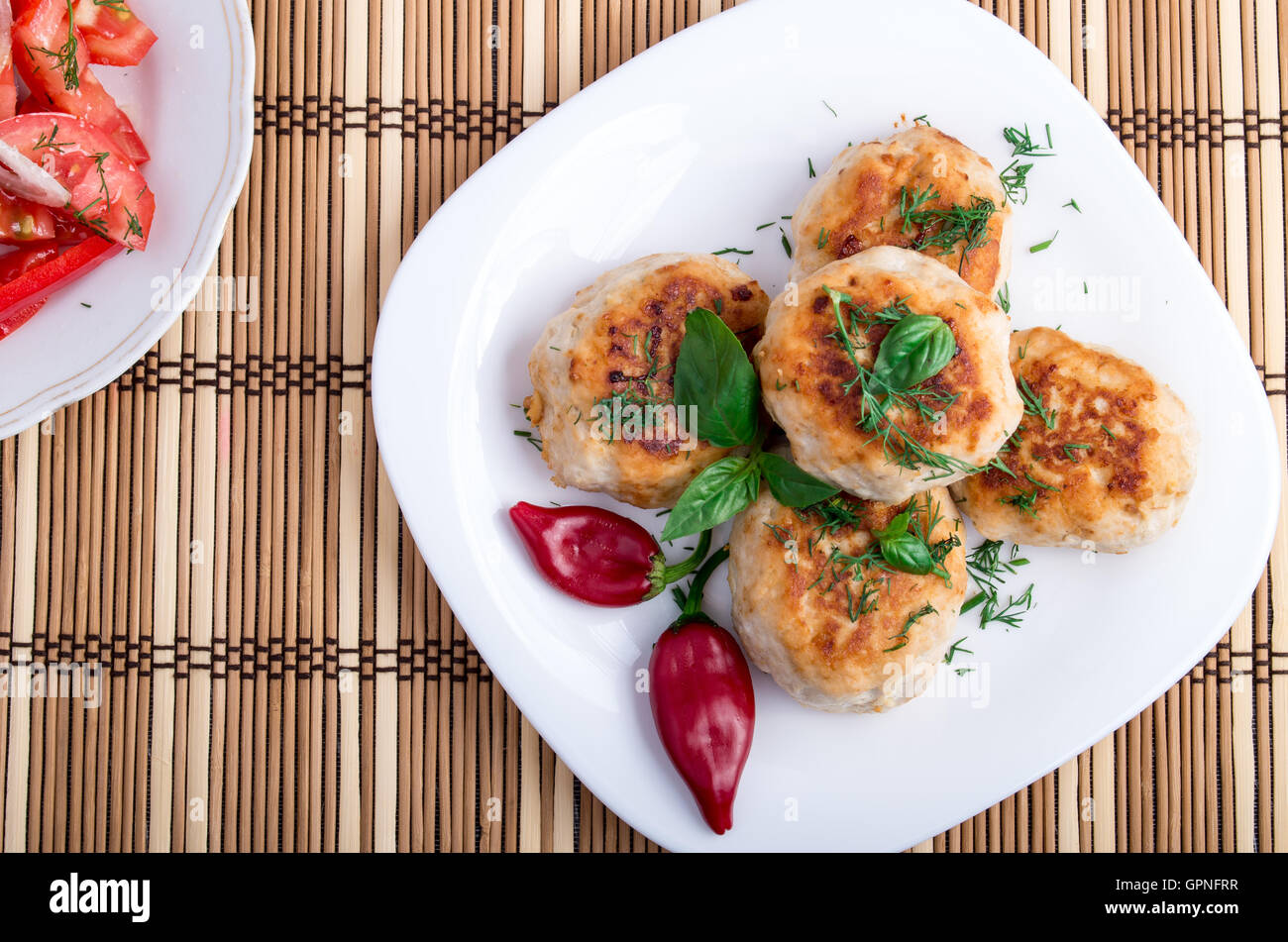 Top view on food made from natural ingredients - chicken meatballs of minced meat and a salad of raw tomatoes on a striped backg Stock Photo
