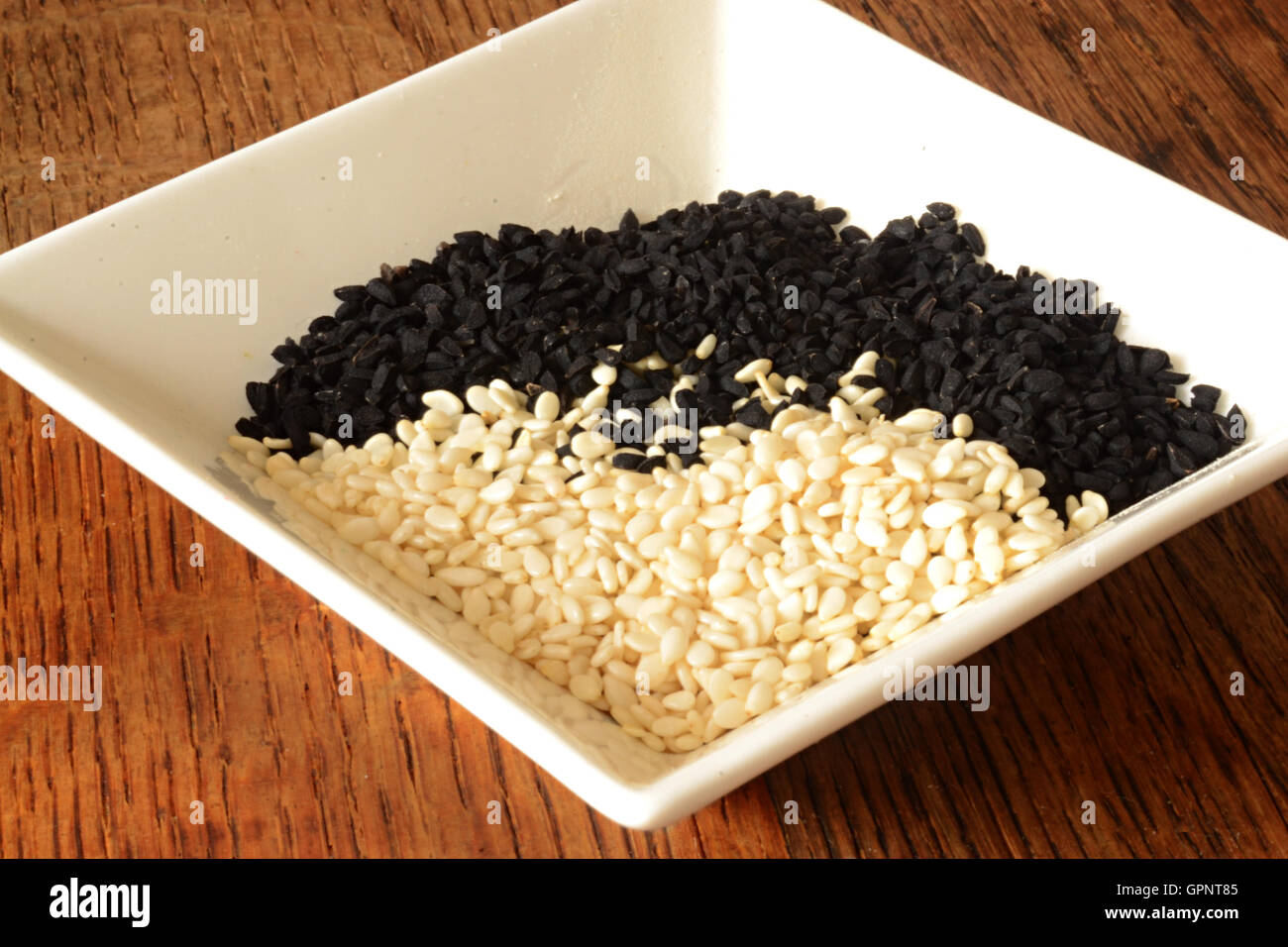 White plate with white sesame seeds and black cumin seeds Stock Photo