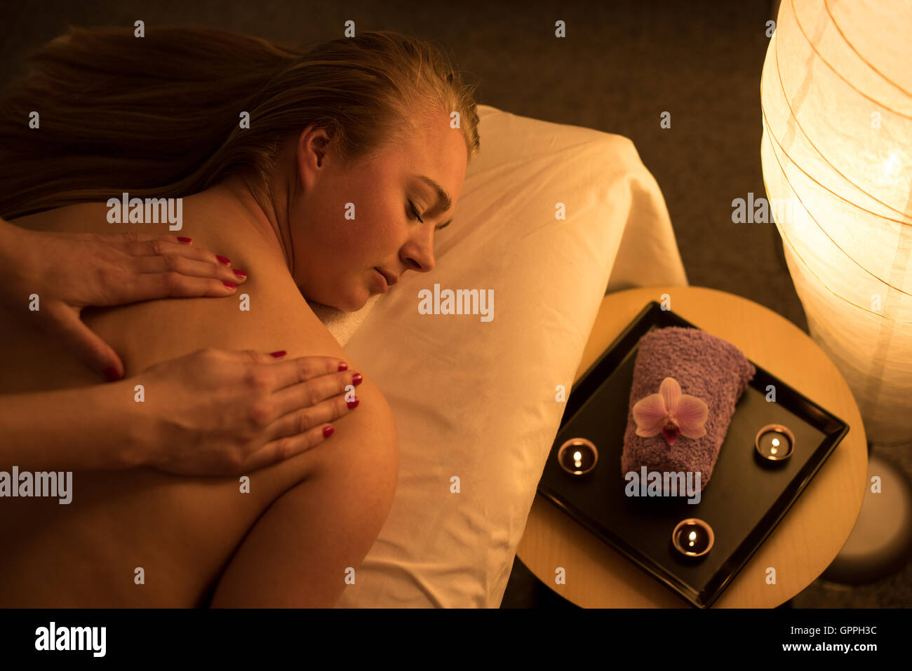 Woman enjoying relaxing back massage in cosmetic spa centre in serene atmosphere. Stock Photo