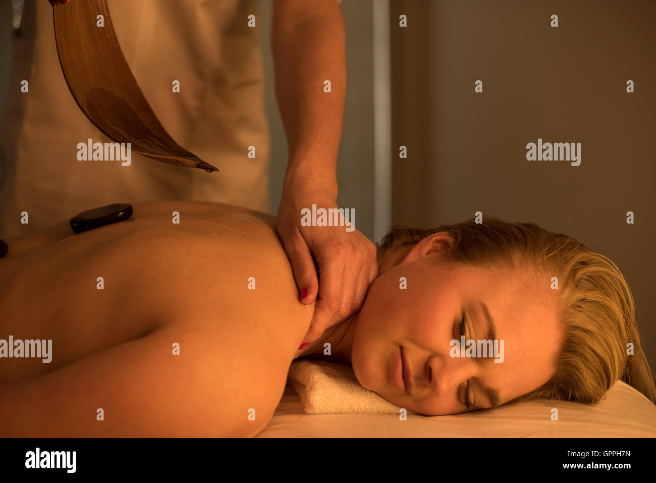Woman enjoying relaxing back massage in cosmetic spa centre in serene atmosphere. Stock Photo