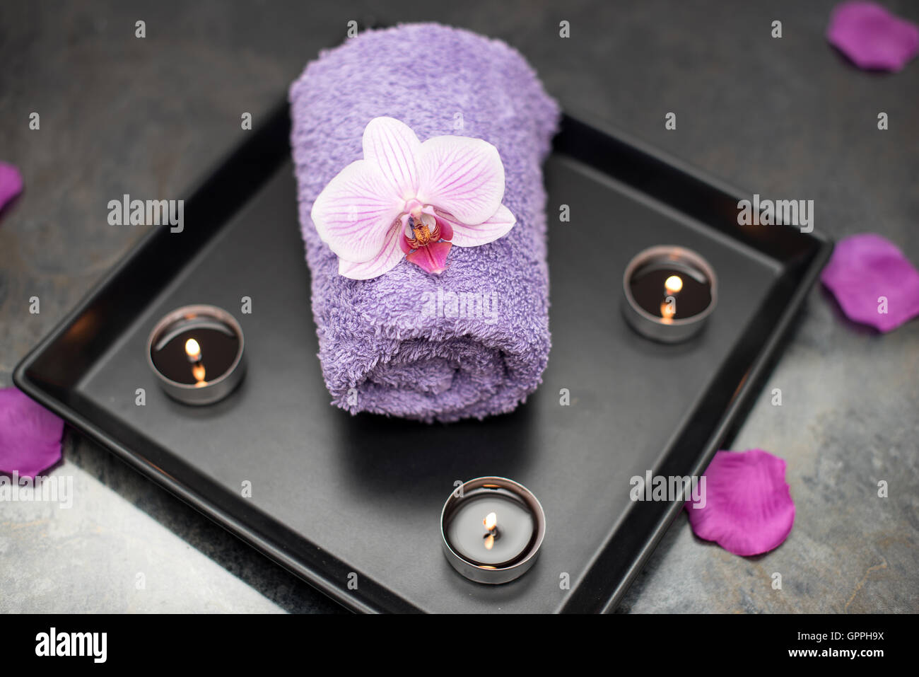 Beauty salon decoration in massage room, candles, towel and orchid. Stock Photo