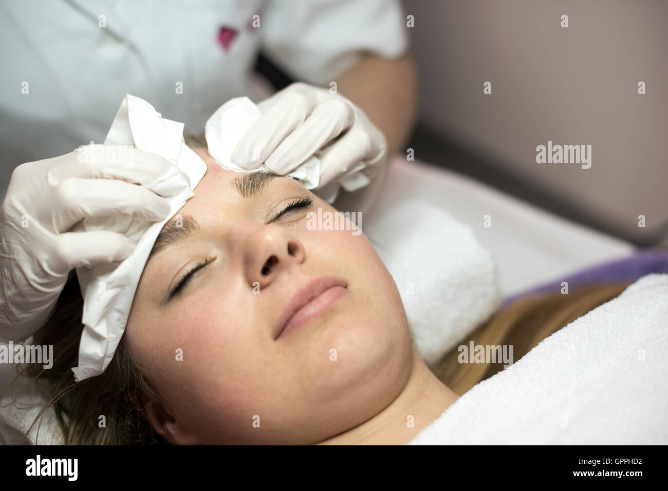 Young woman receiving beauty face therapy of cleaning pimple, acne. Stock Photo