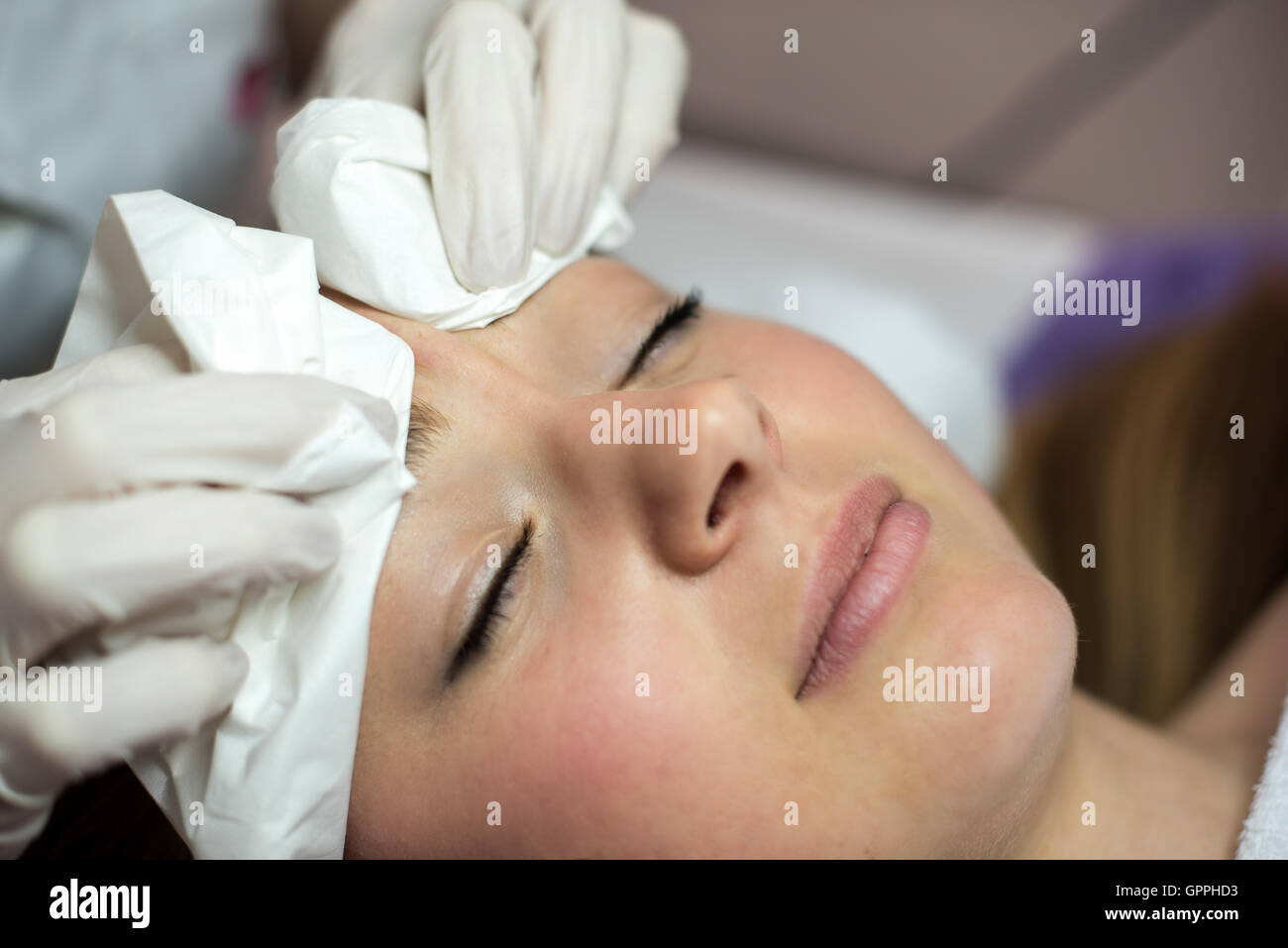 Young woman receiving beauty face therapy of cleaning pimple, acne. Stock Photo