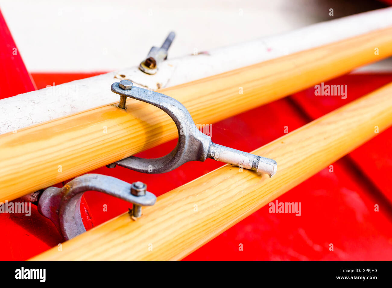 Close up and narrow focus on rowlock on wooden oar lying in red rowboat