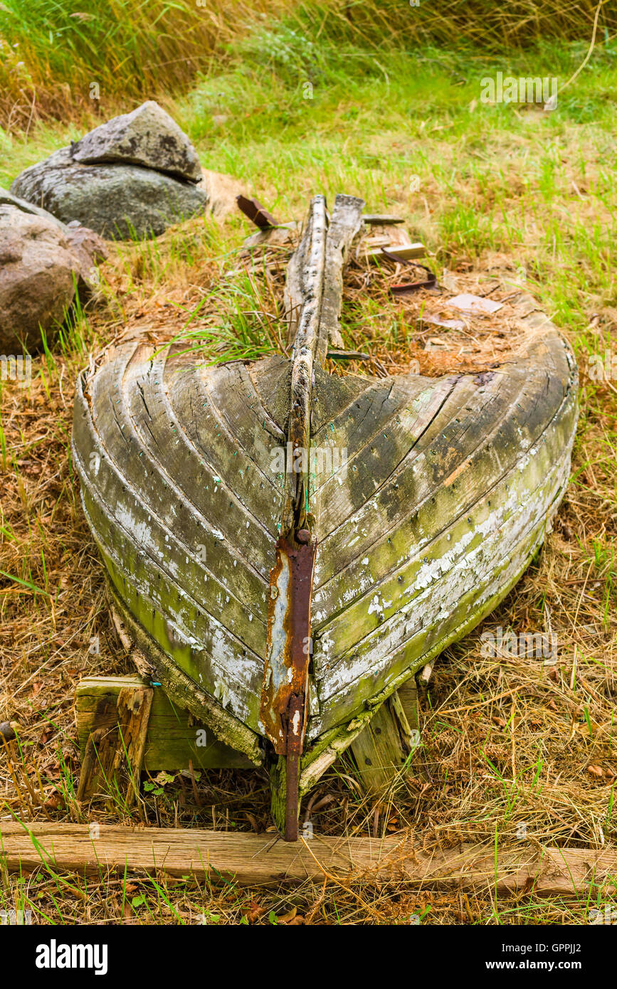 Very old rotting boat lying on dry land wasting away. Nature is slowly reclaiming the material in the abandoned vessel. Stock Photo
