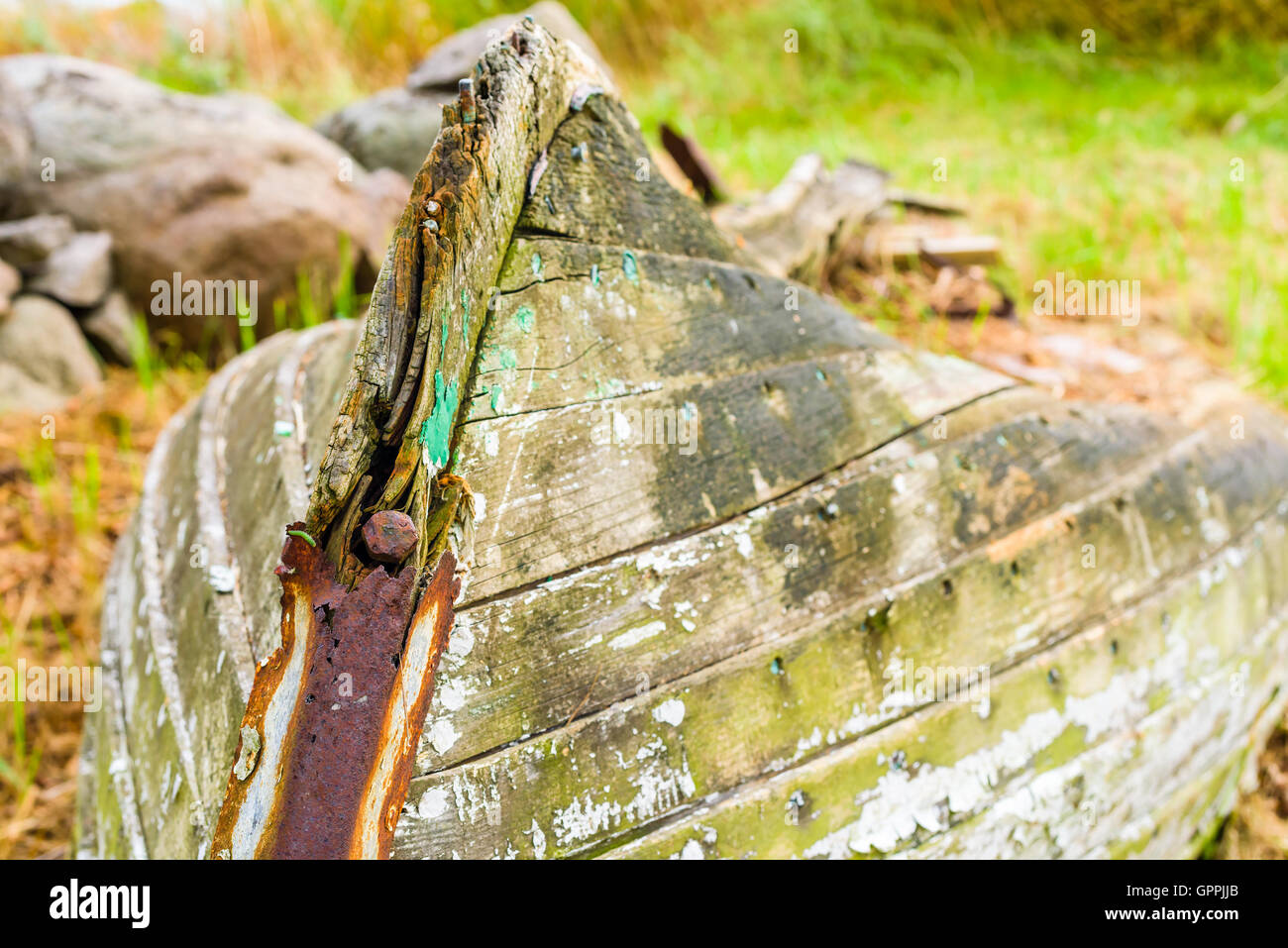 Very old rotting boat lying on dry land wasting away. Nature is slowly reclaiming the material in the abandoned vessel. Stock Photo