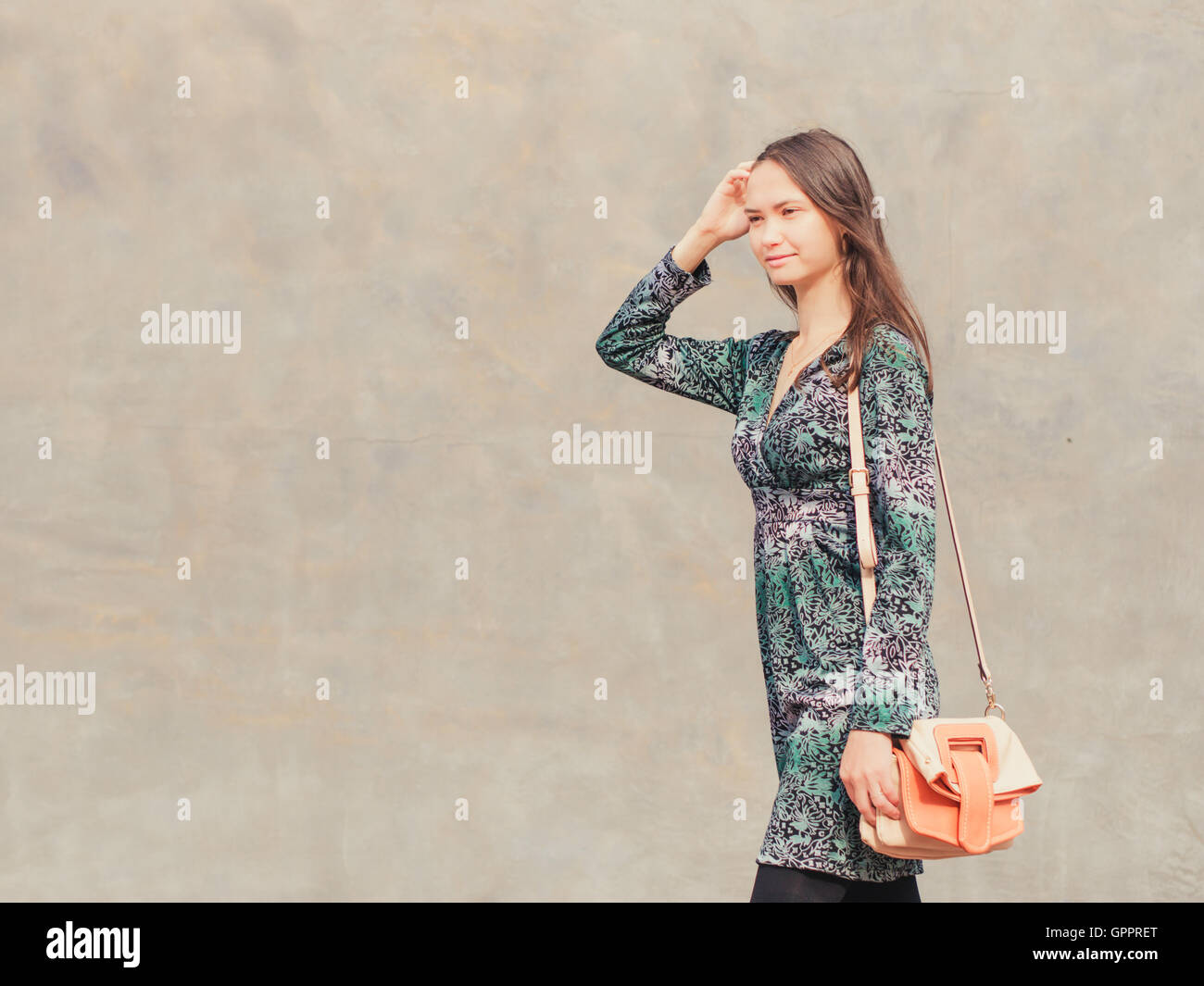 woman walking on street in front of gray wall Stock Photo - Alamy