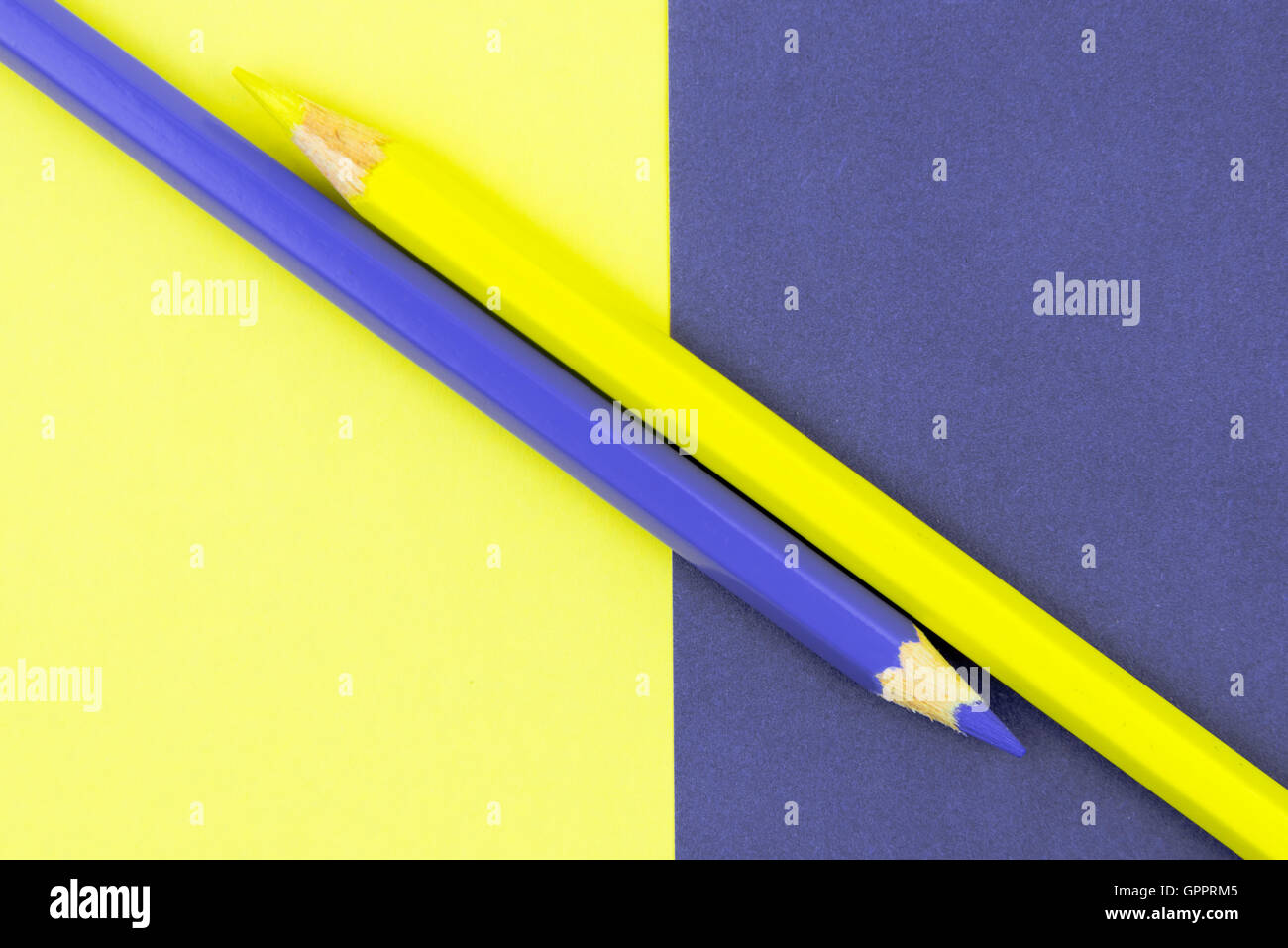 Yellow and Violet coloured pencils and paper, abstract contrast conceptual image Stock Photo