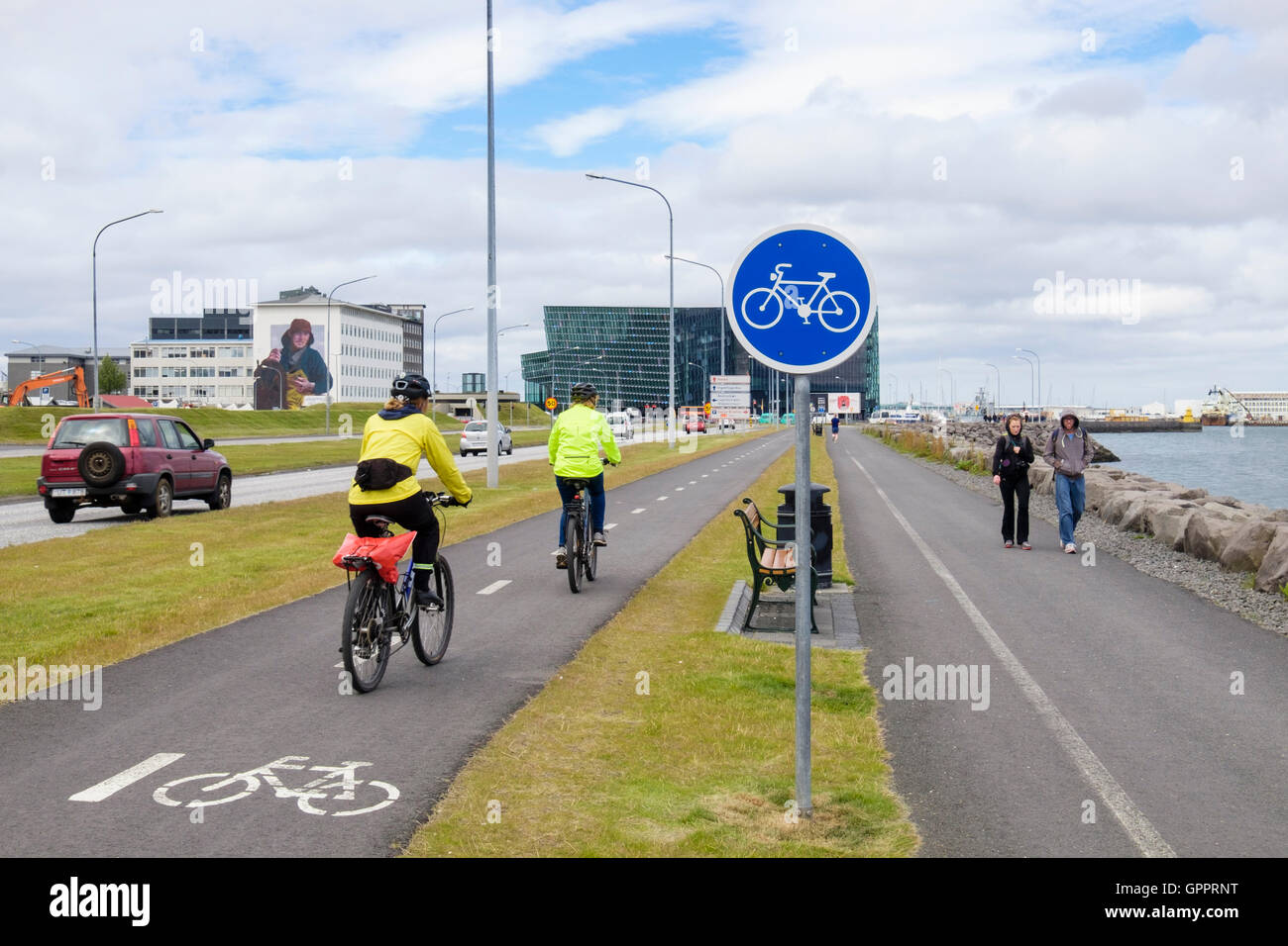 Cyclists riding on cycle track beside pedestrian footway with bicycle sign on the waterfront promenade. Reykjavik, Iceland Stock Photo