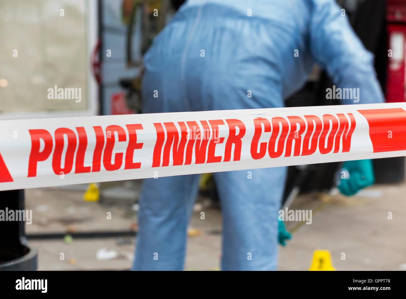 Police inner cordon tape barrier and a scene of crime officer / officers, & evidence identification number marker / markers. UK Stock Photo