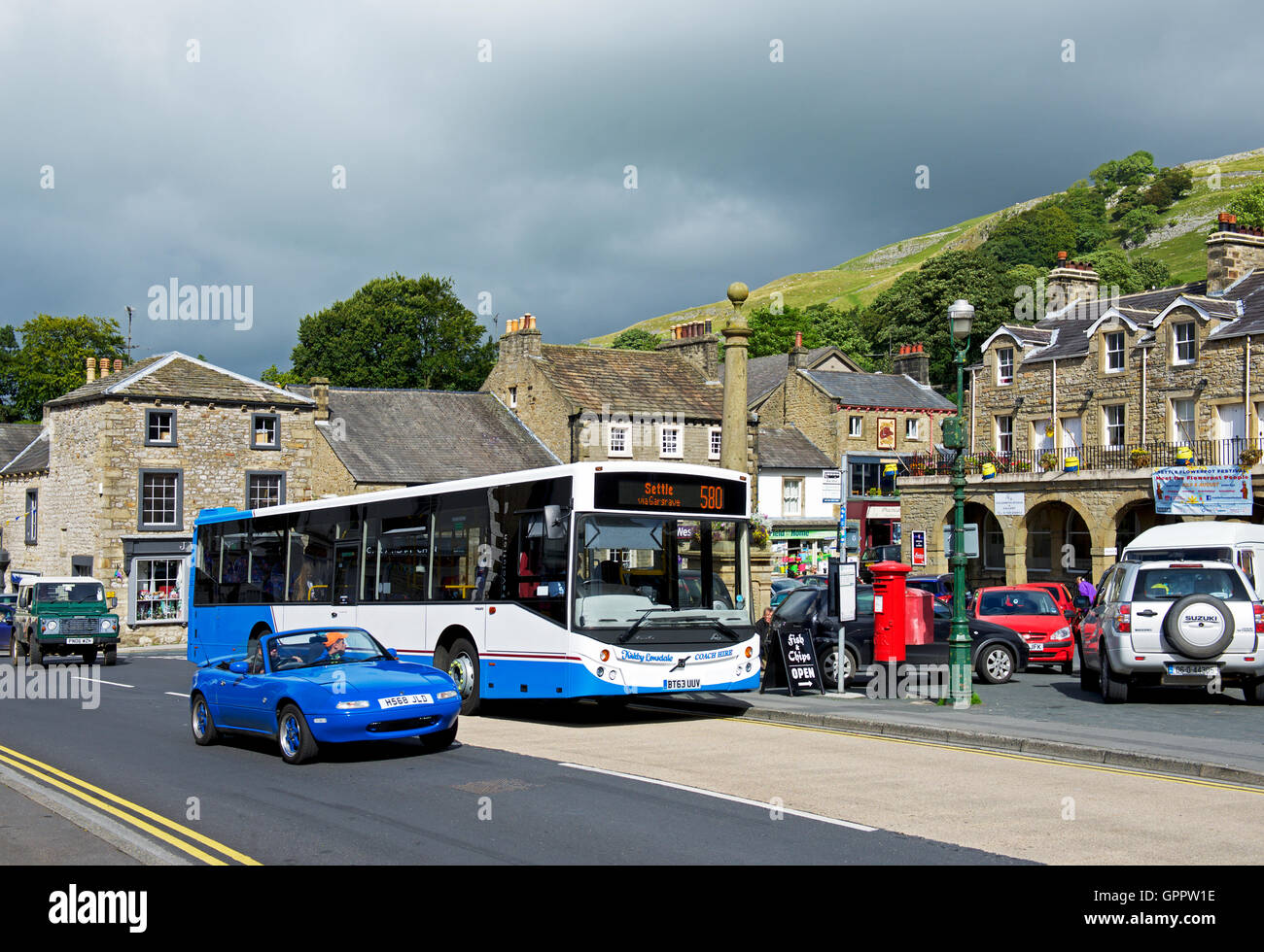 Bus and sports car in the market place, Settle, North Yorkshire, England UK Stock Photo