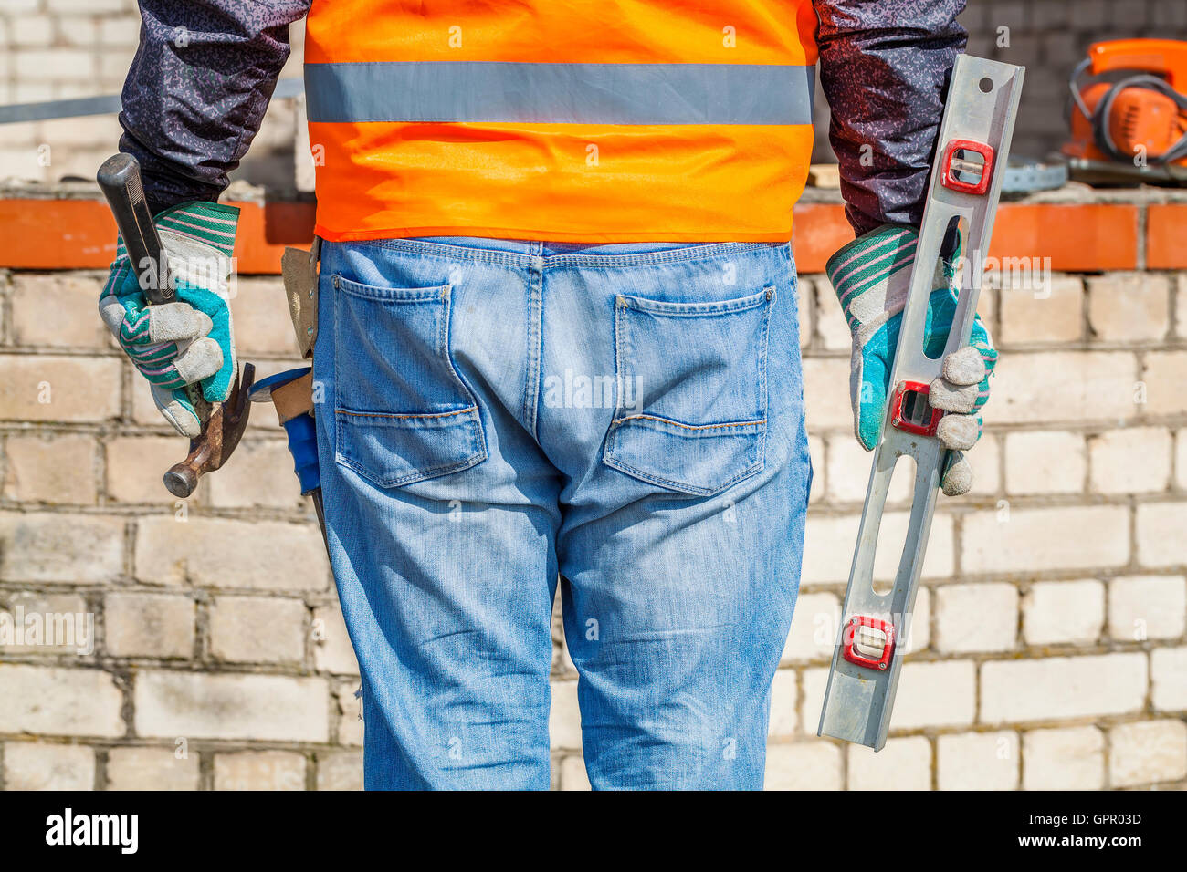 Builder with spirit level and hammer Stock Photo - Alamy