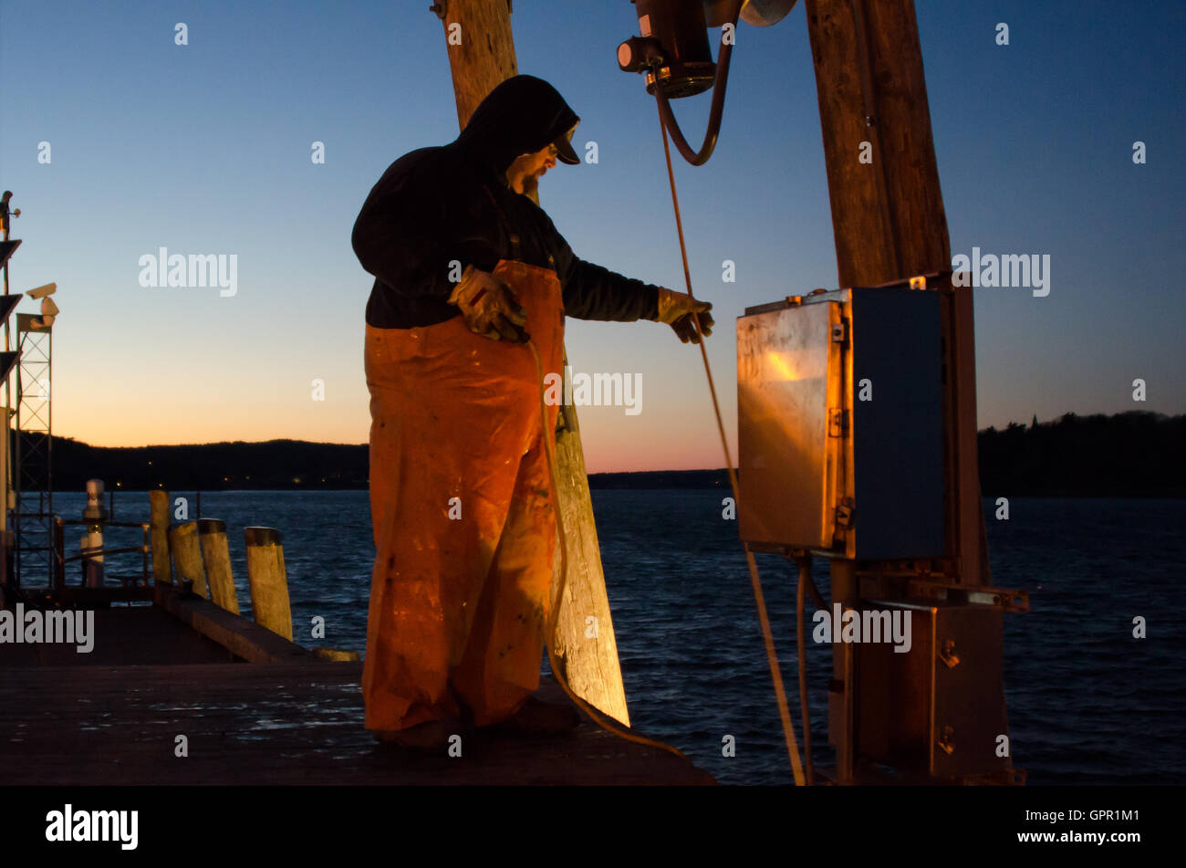 A fisherman unloads his boat at the Town Dock on a cold December evening in Bar Harbor, Maine. Stock Photo
