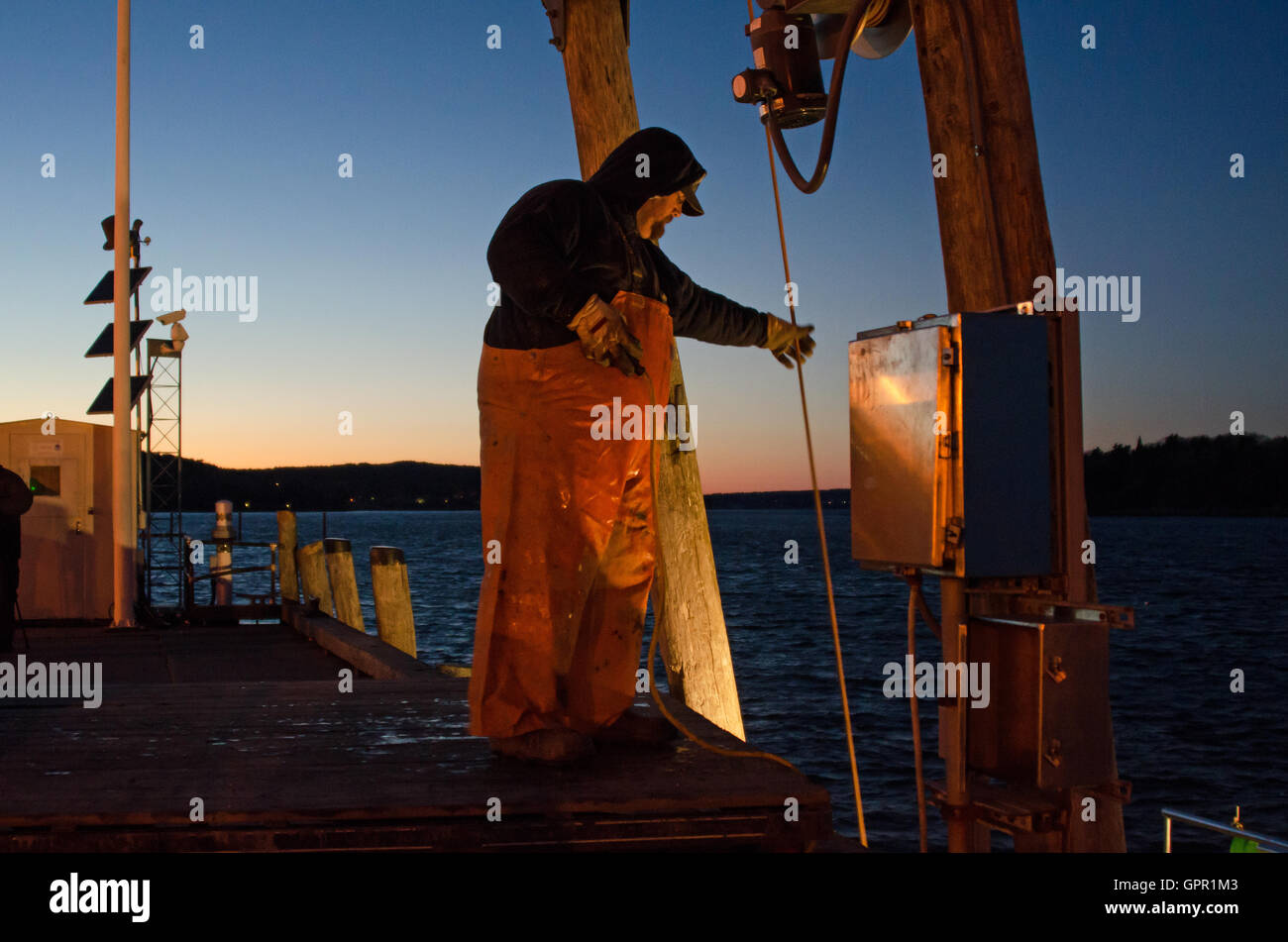 A fisherman unloads his boat at the Town Dock on a winter evening in Bar Harbor, Maine. Stock Photo
