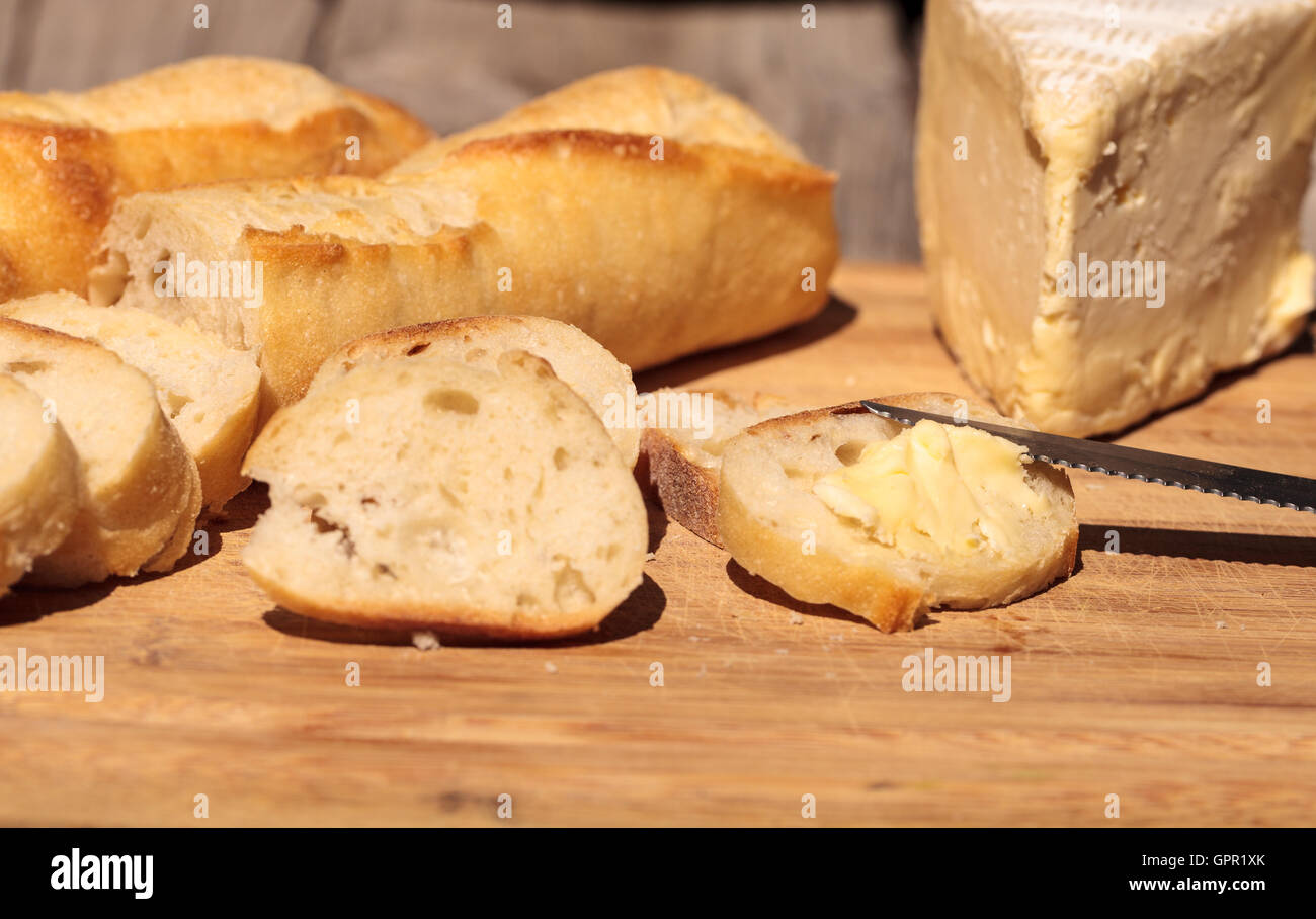 French bread and triple cream brie cheese on a cutting board with a knife. Stock Photo