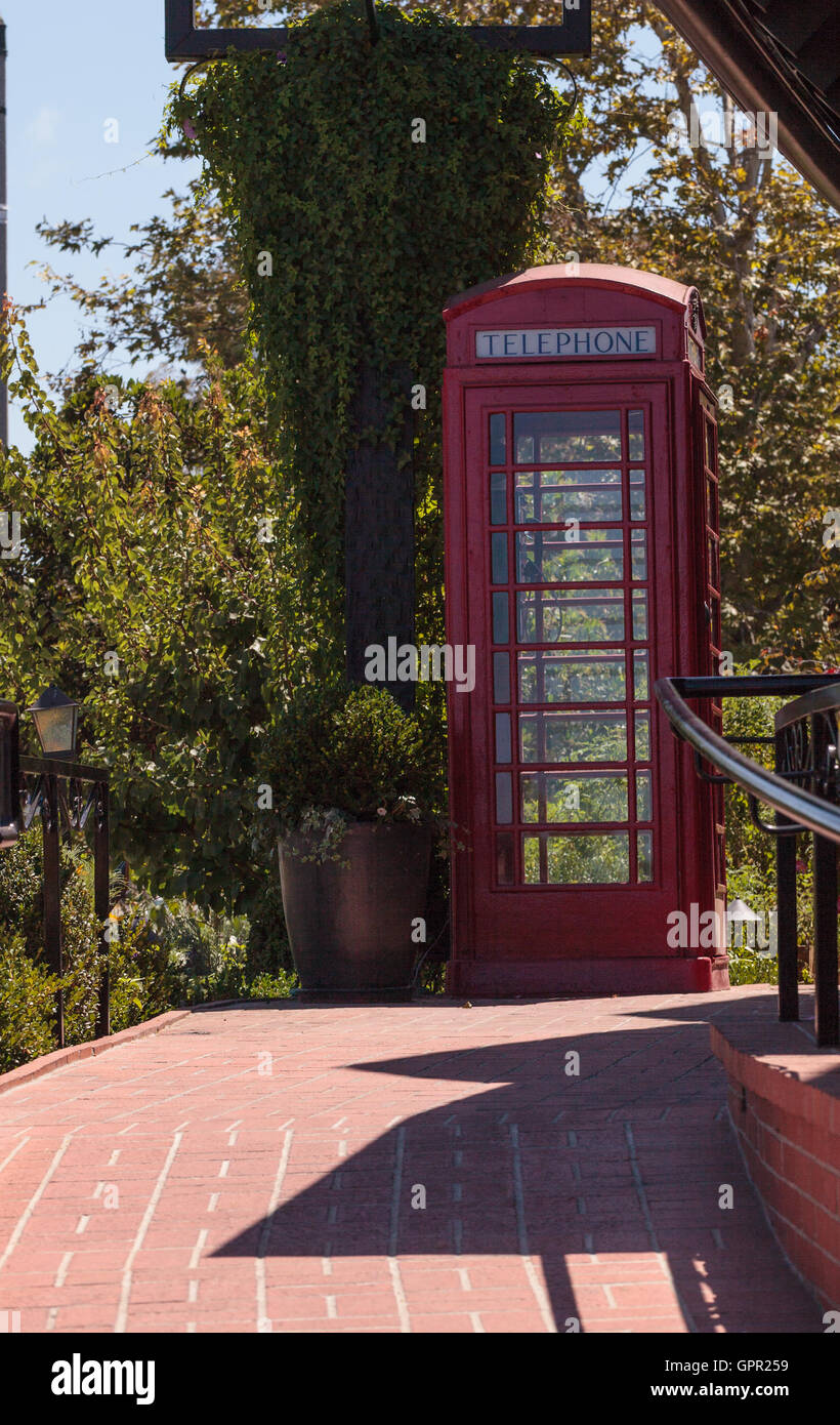 Old fashioned antique classic red phone booth outside in the summer. Stock Photo