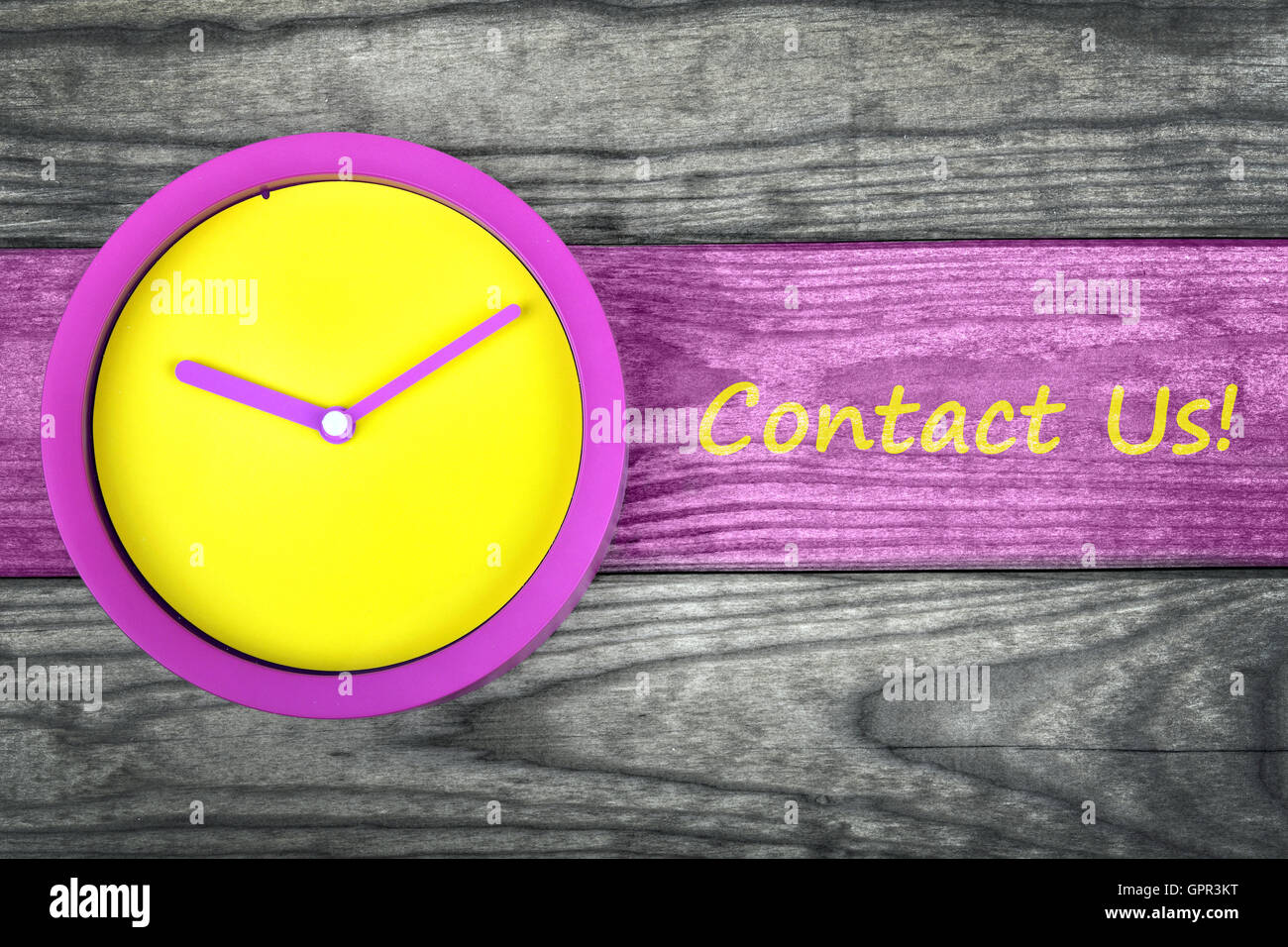 Contact Us message and clock on wooden table Stock Photo