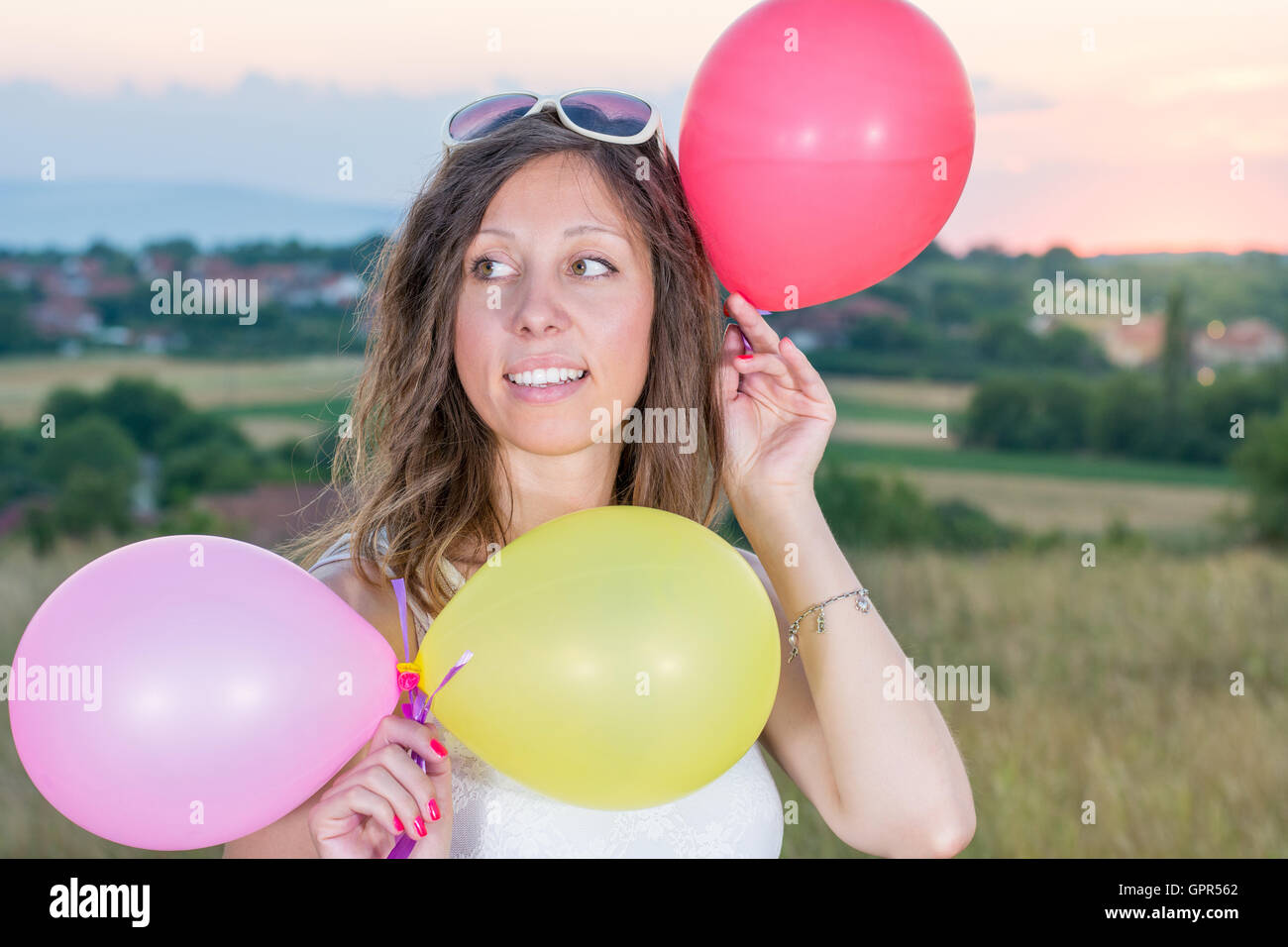 Young woman holding balloons at romantic sunset Stock Photo