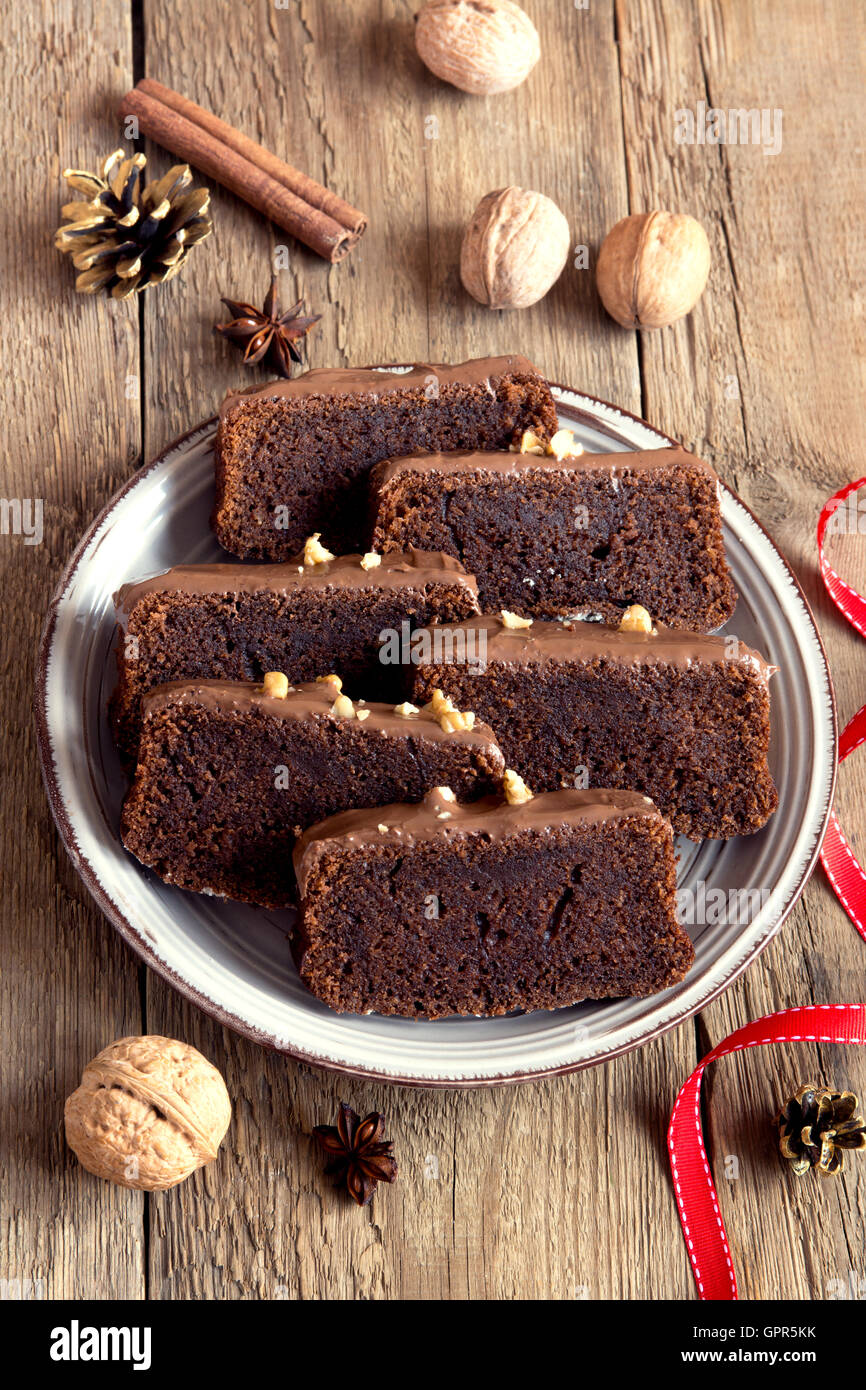 Chocolate sliced cake with nuts and spices for Christmas over rustic wooden background Stock Photo