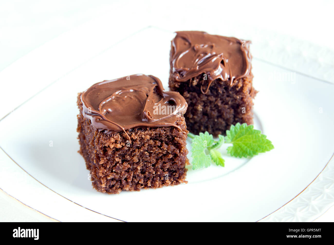 Chocolate mini cakes with chocolate icing and mint on white plate close up Stock Photo