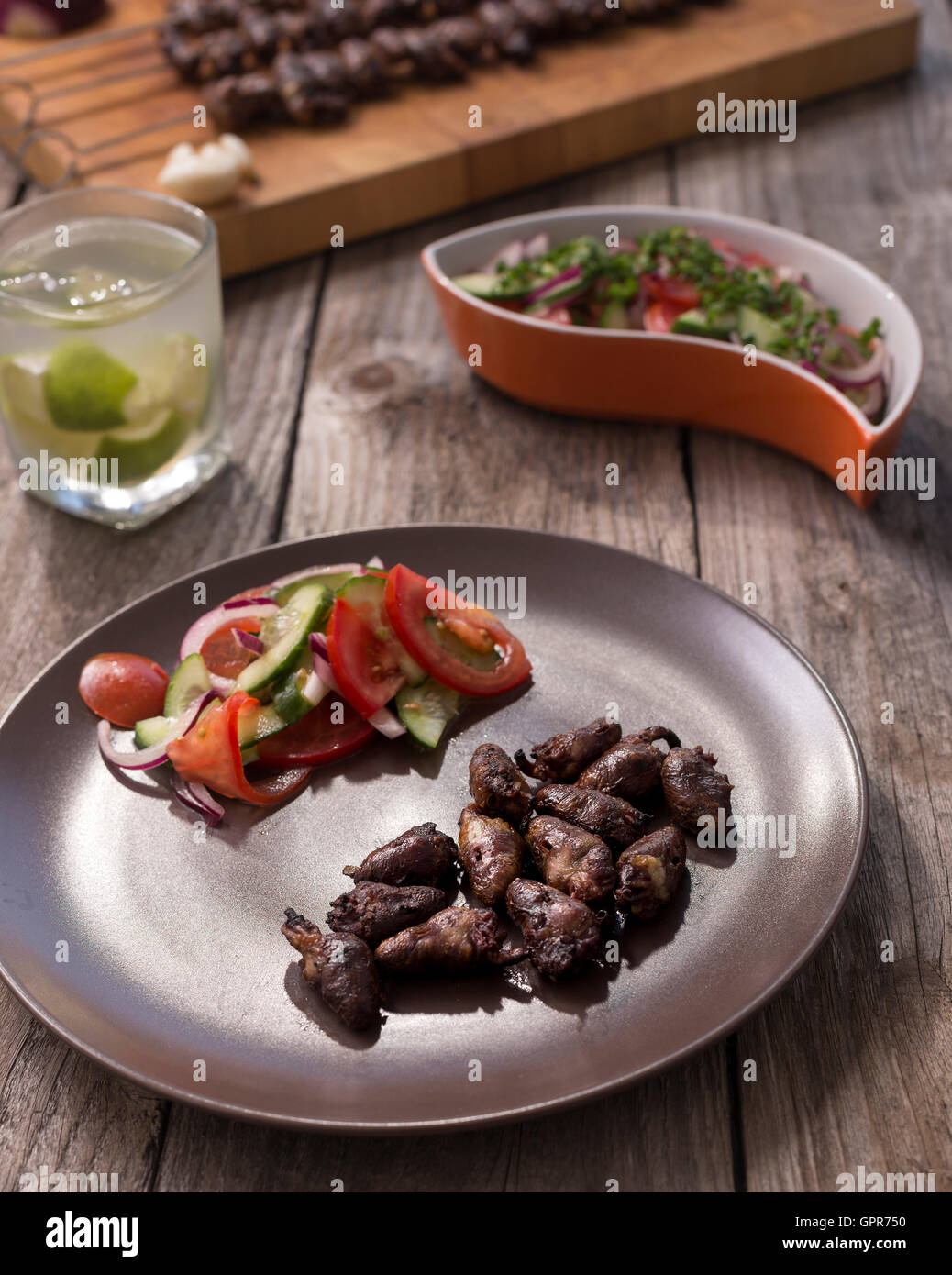 'Churrasco de curacao',traditional Brazilian barbecue food, grilled chicken hearts composition with tomatoes and onion salad an  Stock Photo