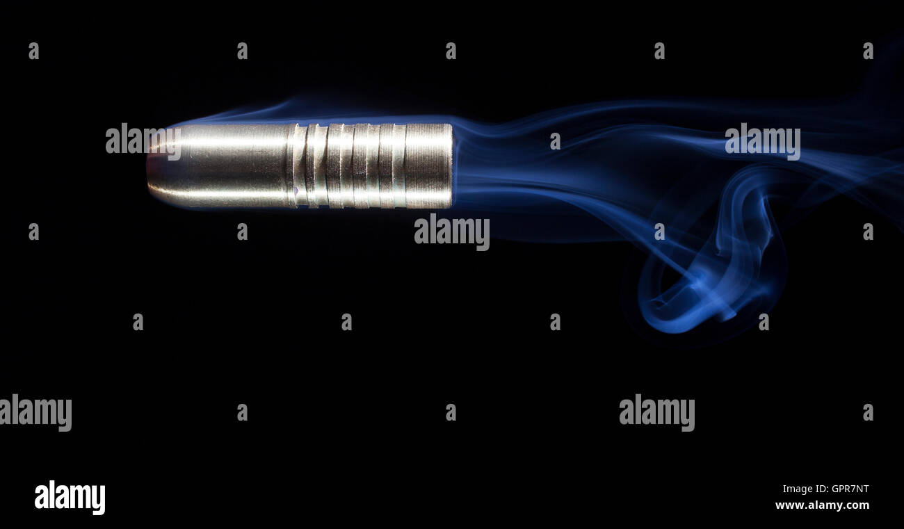 Large rifle bullet with grooves on a black background with smoke Stock Photo
