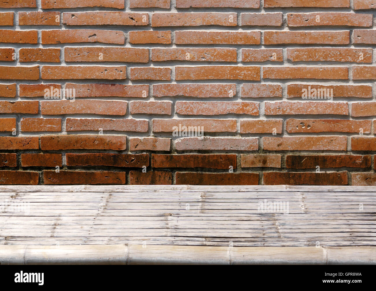 Bamboo wicker table on grunge orange brick wall Stock Photo