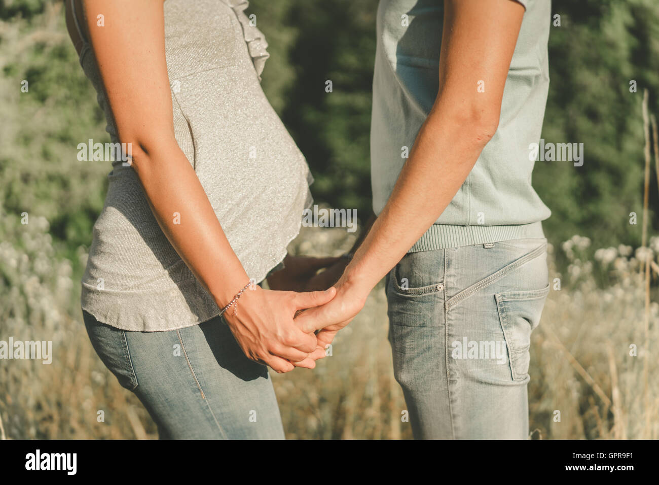 Couple expecting a child holding hands with love facing each other. Stock Photo